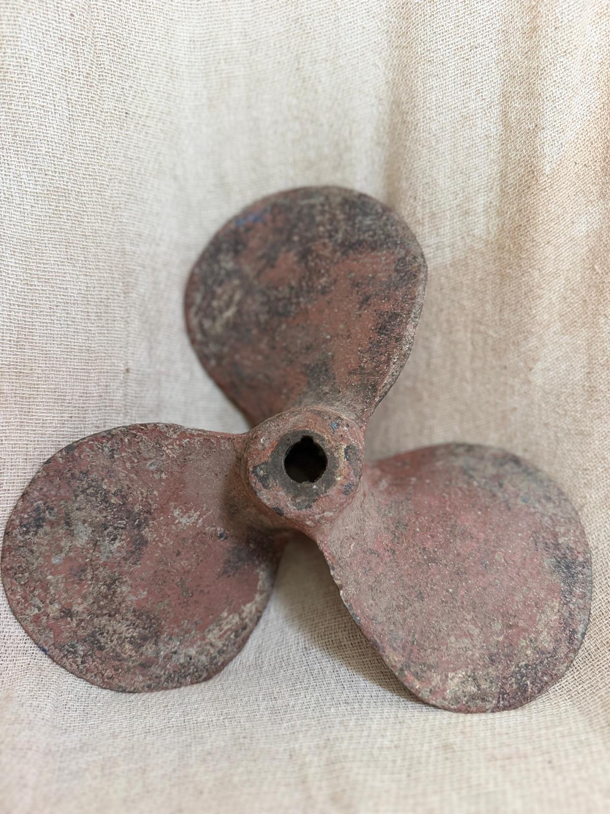 Rust-colored propeller on a textured beige background