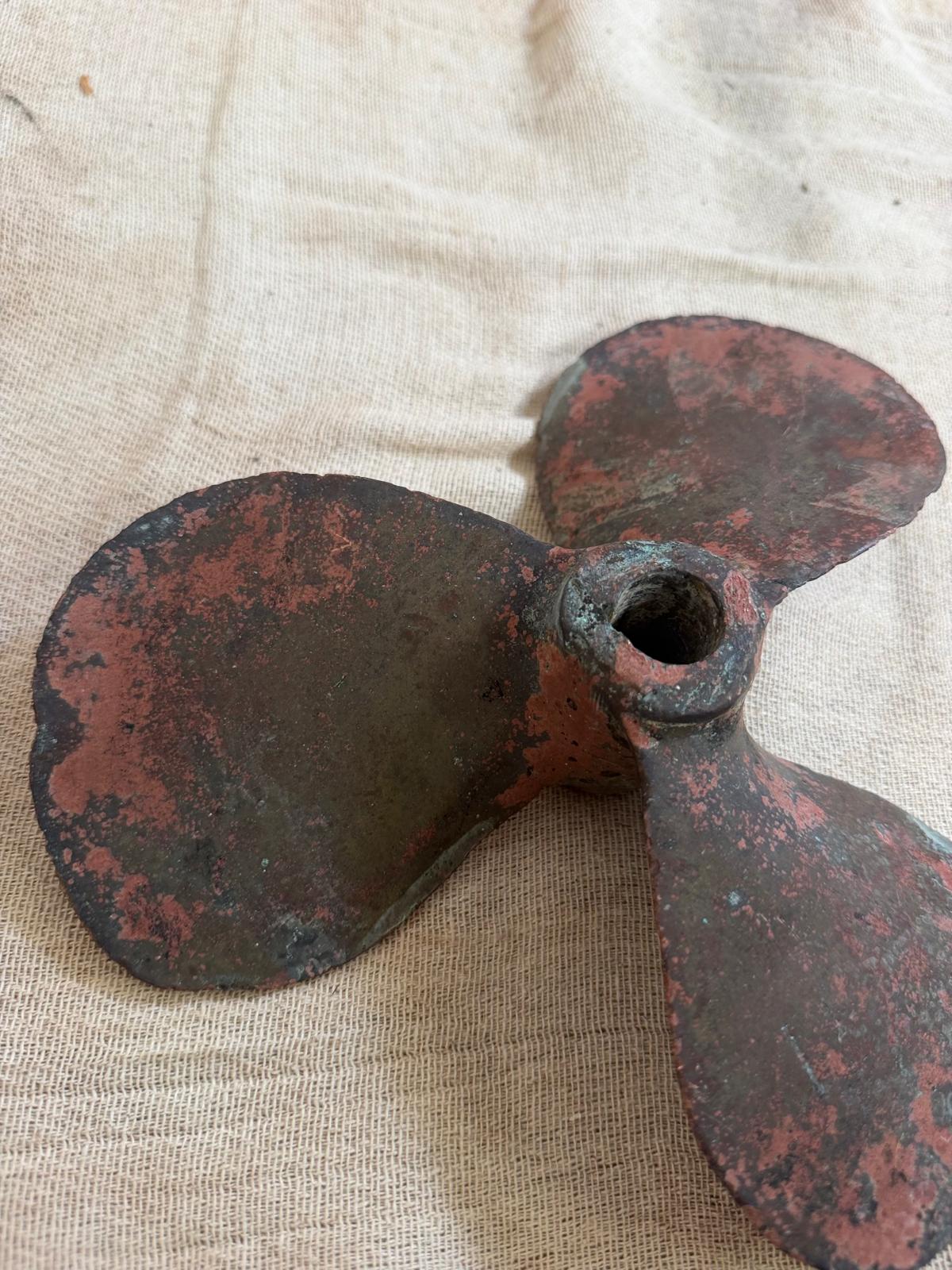 Rust-colored metal propeller on a beige fabric background