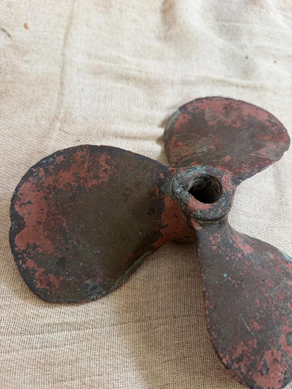 Rust-colored metal propeller on a beige fabric background