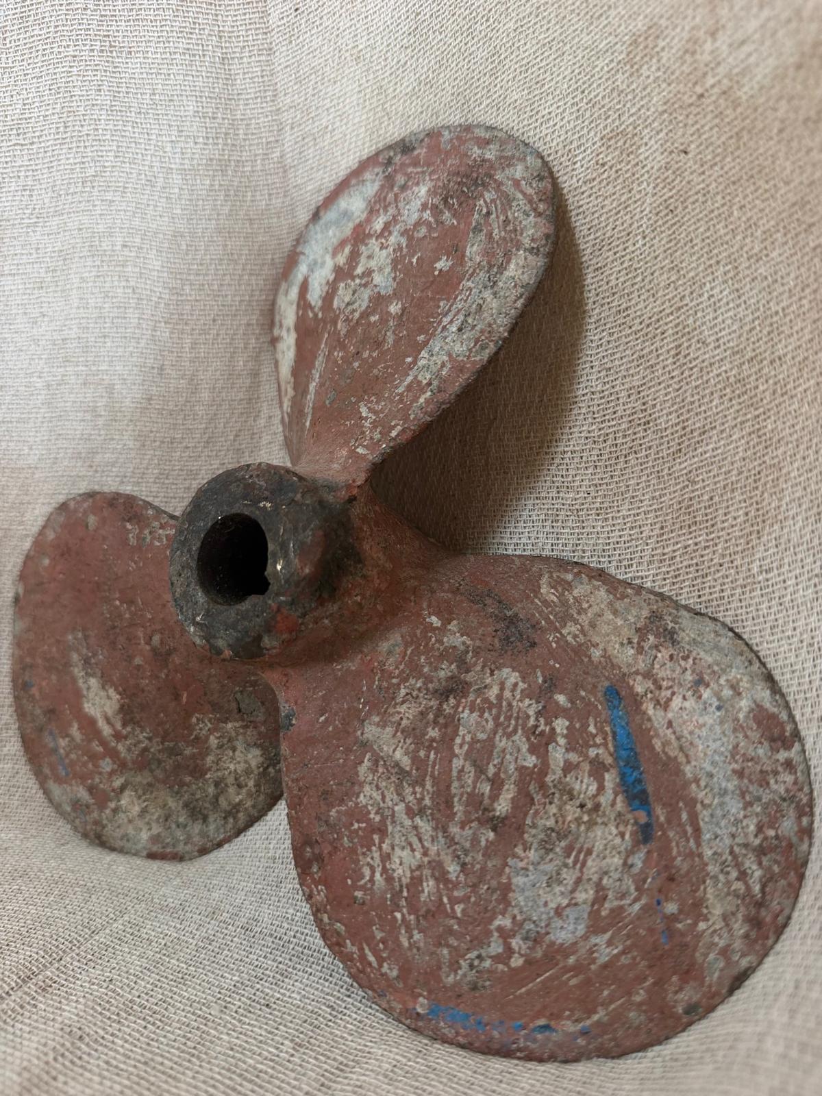 Rust-colored propeller on a textured beige background