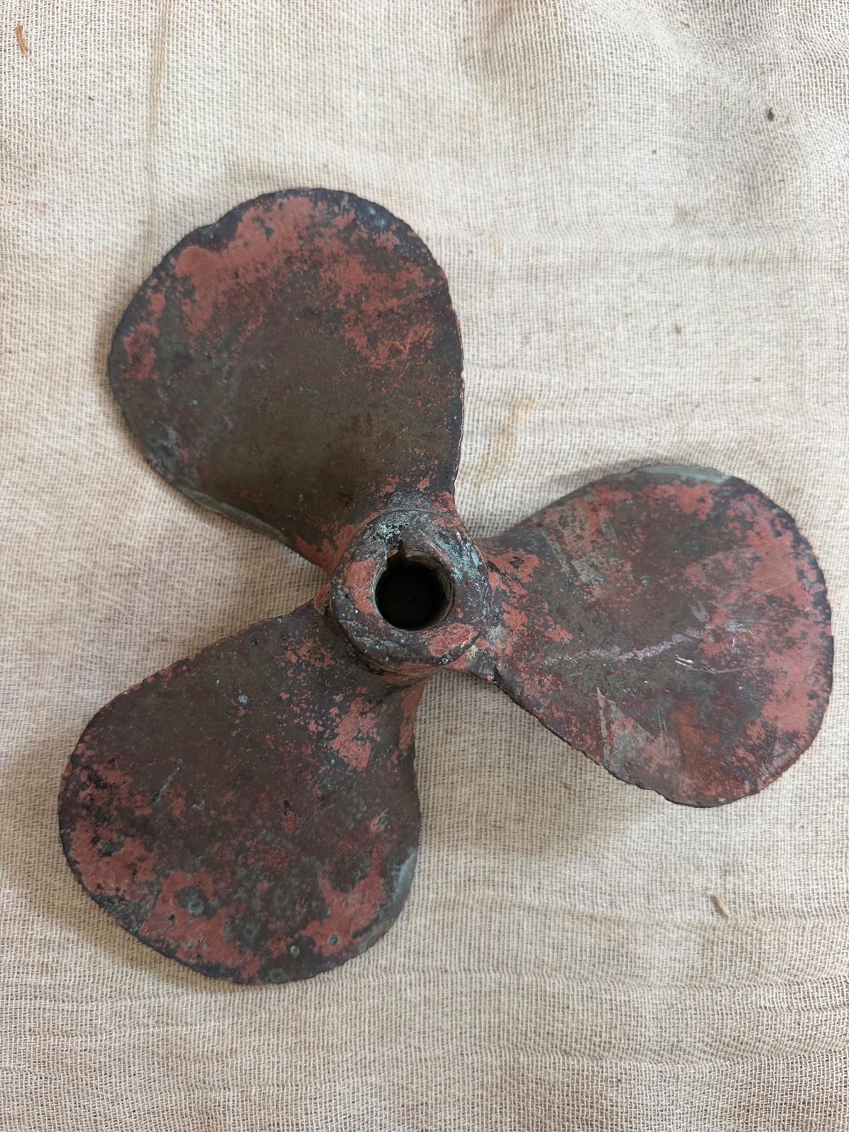 Rusticated metal propeller on a textured fabric background