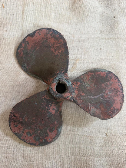 Rusticated metal propeller on a textured fabric background