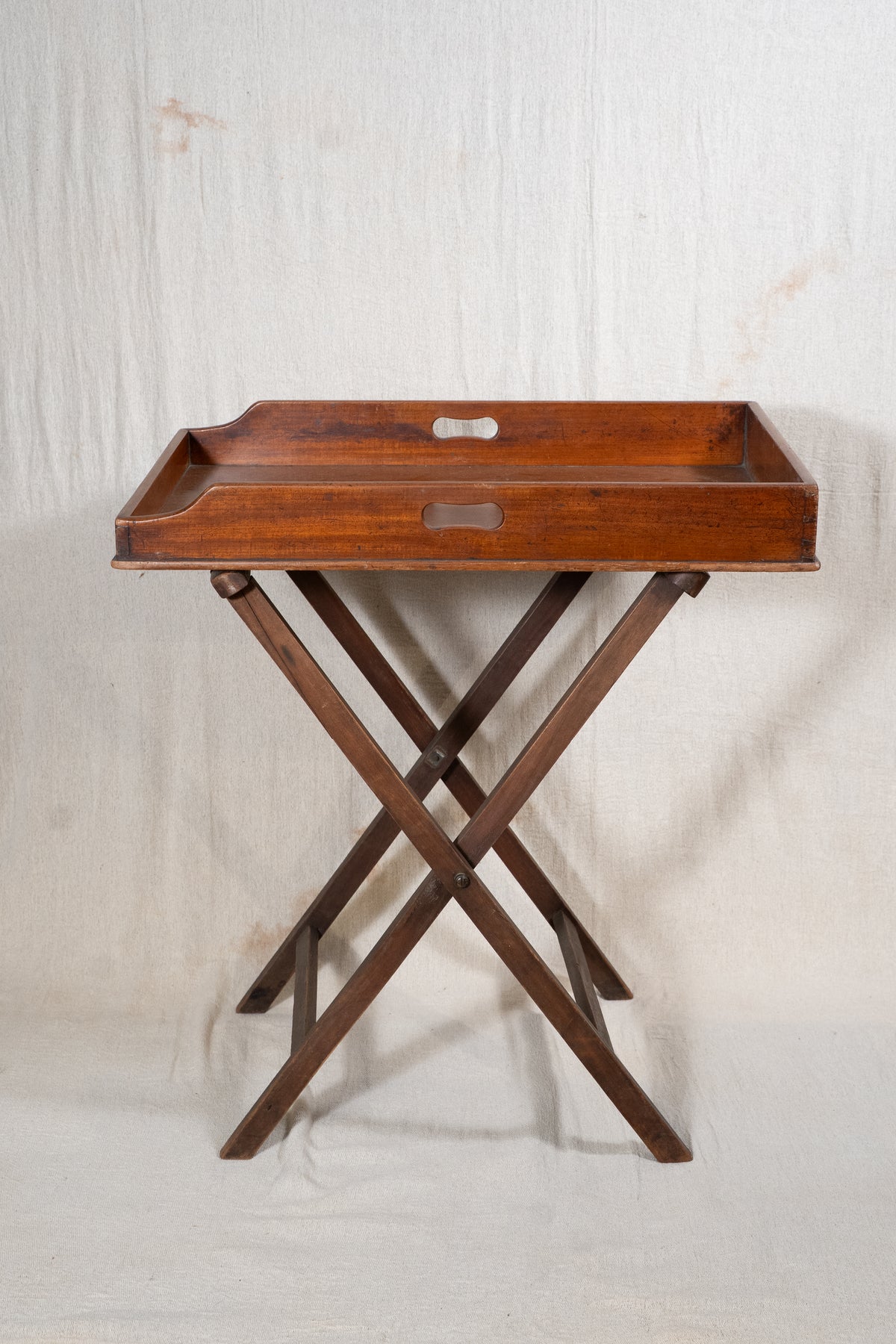 Classic wooden butler's tray with raised gallery, pierced carrying handles and folding X-frame stand. A versatile serving and occasional table.
