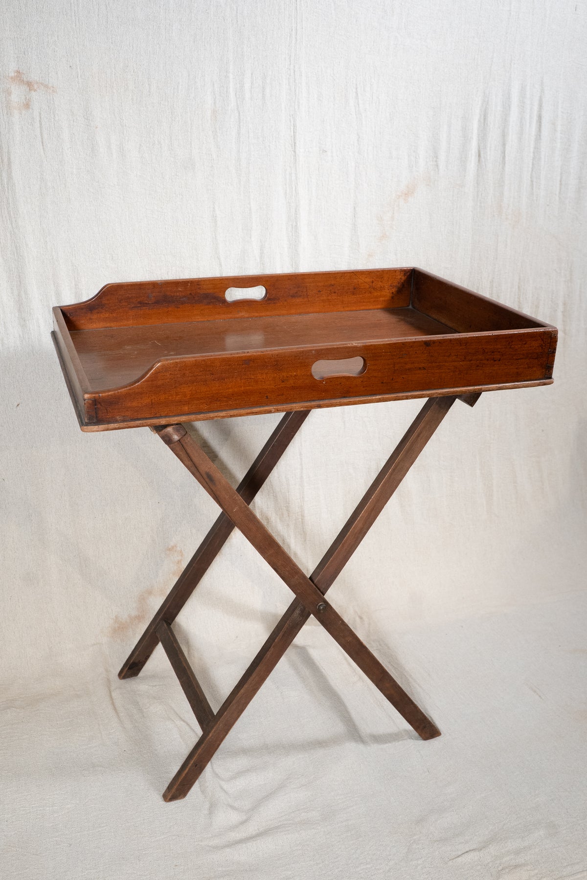 Classic wooden butler's tray with raised gallery, pierced carrying handles and folding X-frame stand. A versatile serving and occasional table.
