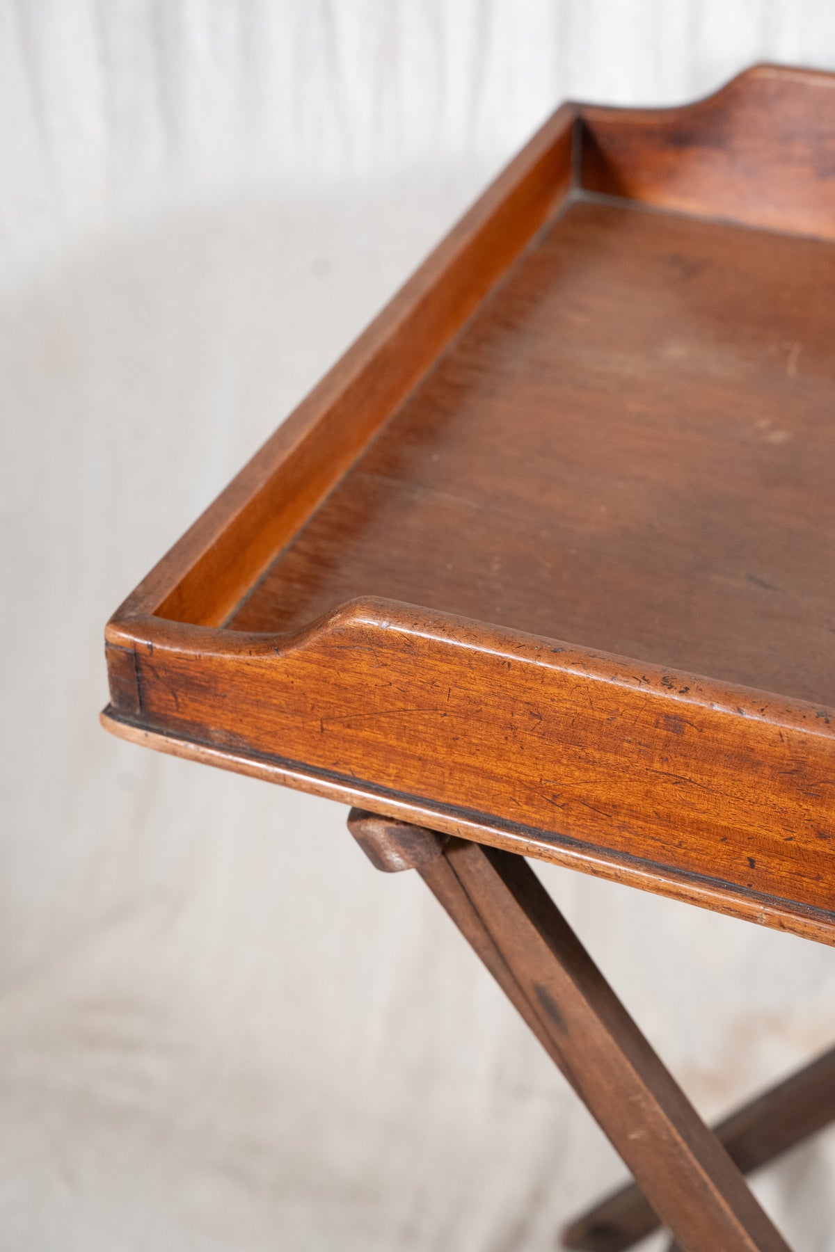 Classic wooden butler's tray with raised gallery, pierced carrying handles and folding X-frame stand. A versatile serving and occasional table.