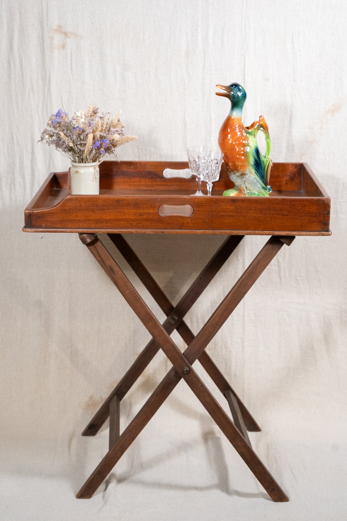 Classic wooden butler's tray with raised gallery, pierced carrying handles and folding X-frame stand. A versatile serving and occasional table.