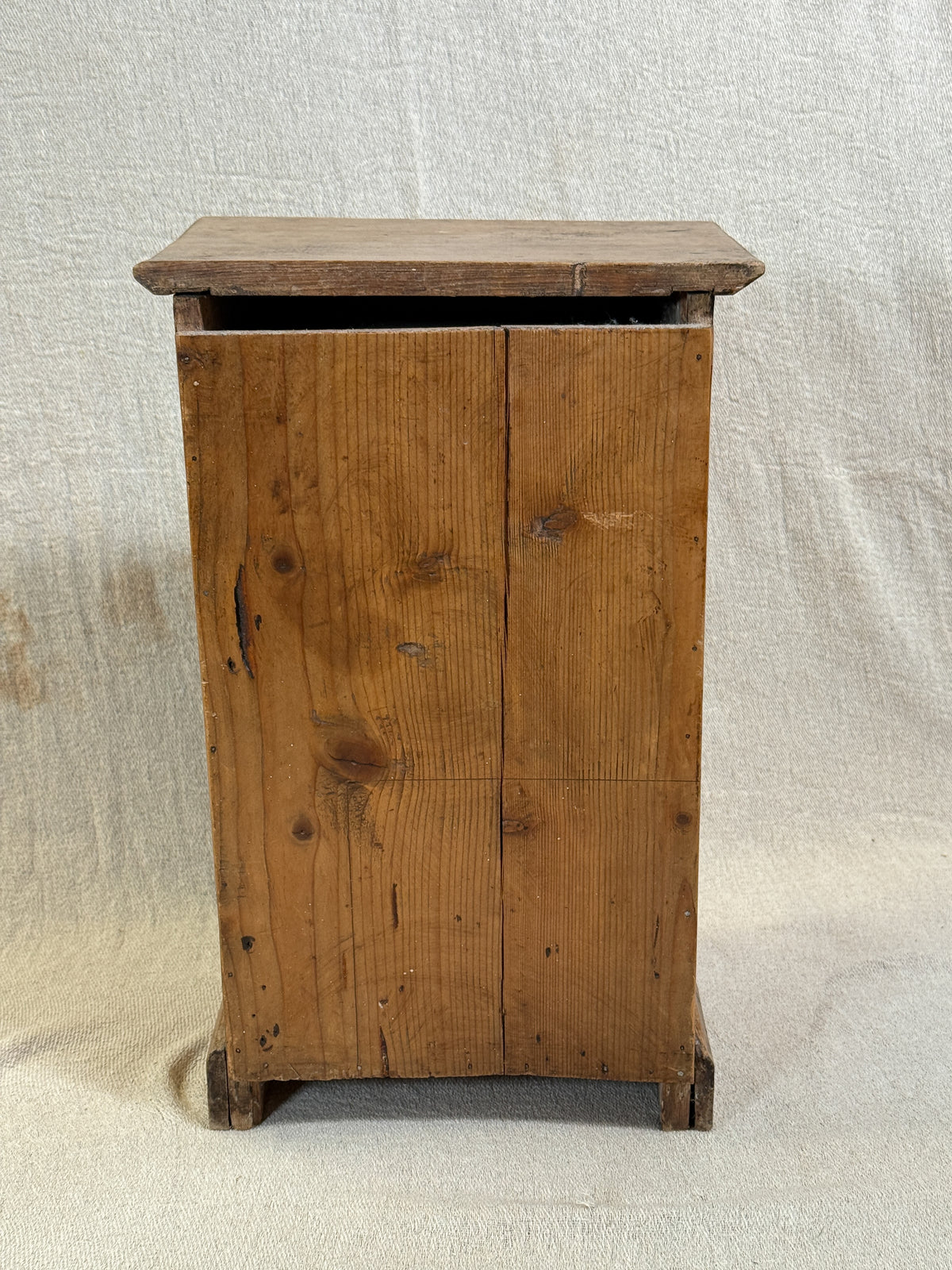 Wooden bedside cabinet with patterned fabric-inset door, braided gimp trim, tassel knob and carved egg-and-dart detailing. 