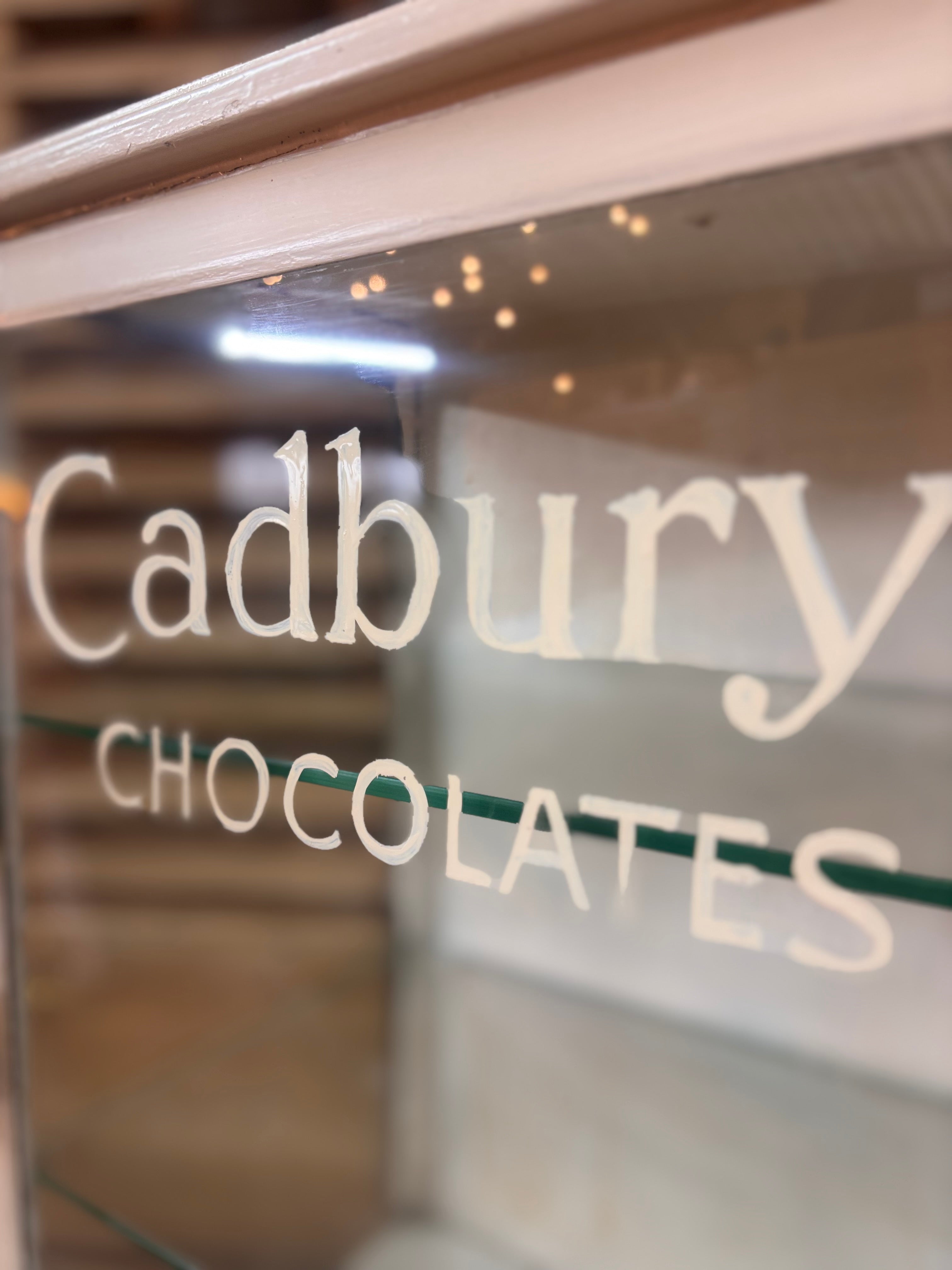 White painted metal Cadburys chocolate display cabinet with glass front, original lettering and aged patina.