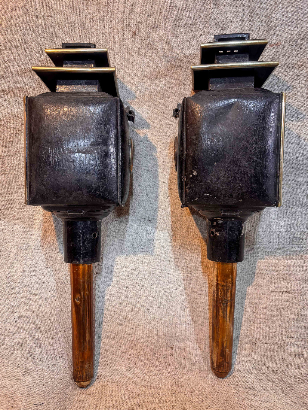 Rear of Two antique carriage lanterns on a textured surface