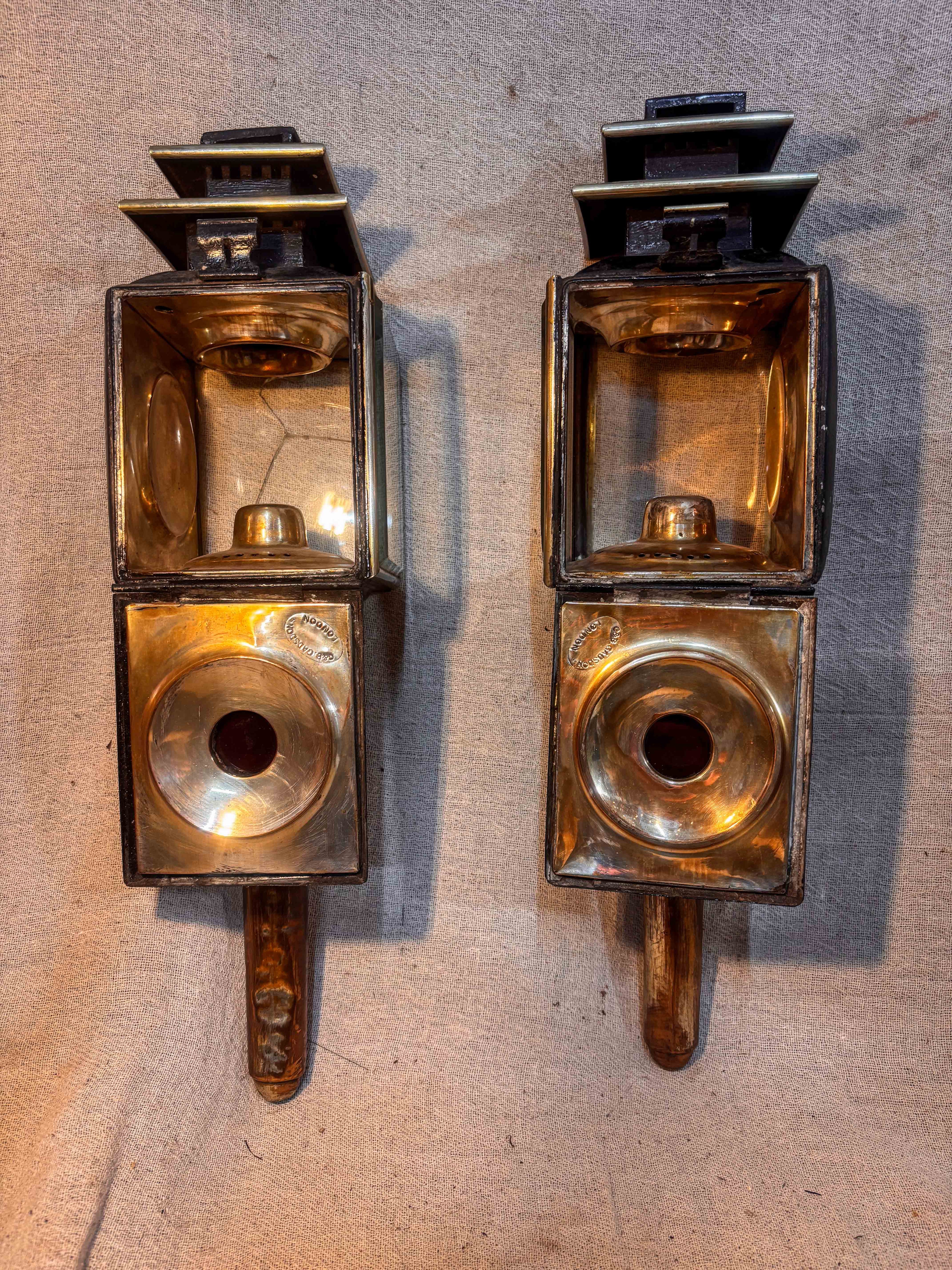 Pair of Antique carriage lamps showing the interior workings on a textured beige background