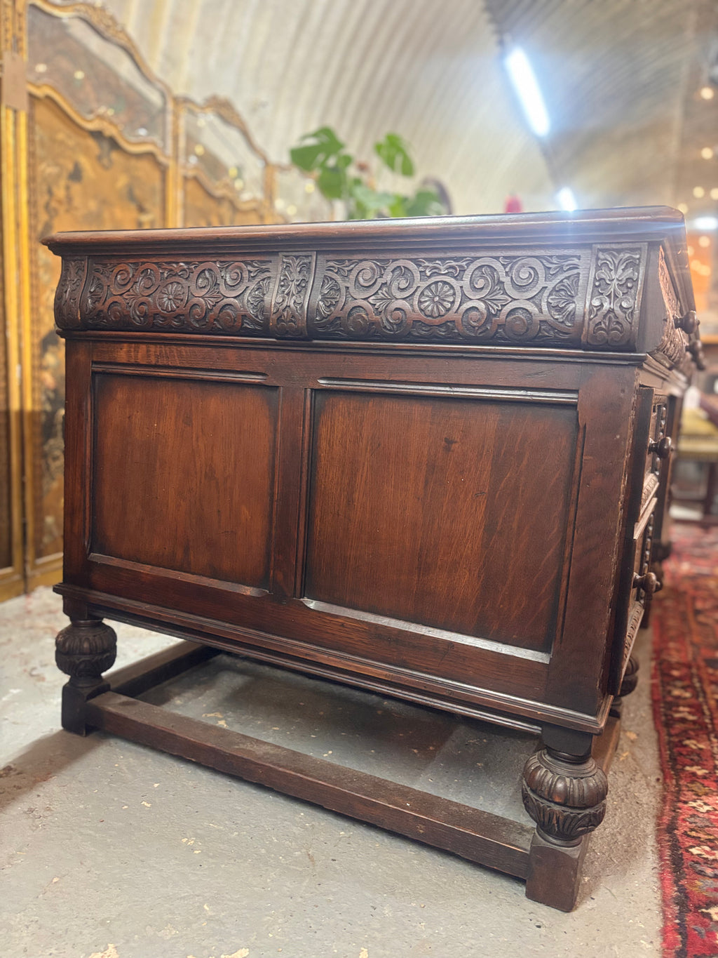 Decorative wooden desk with intricate carvings on a textured floor.