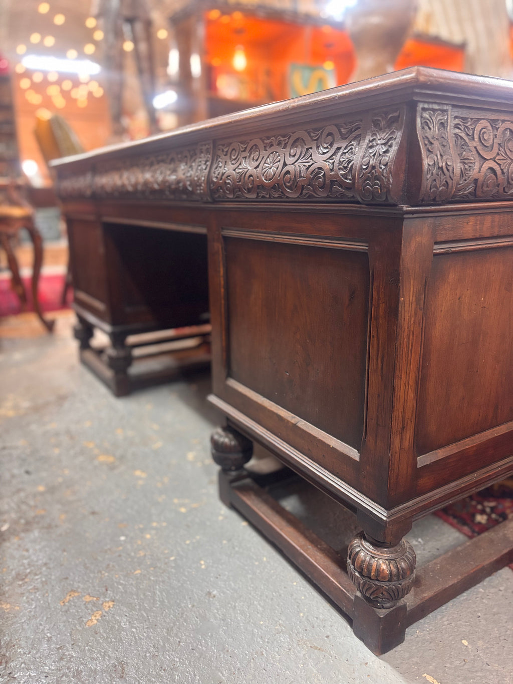 Decorative wooden desk with intricate carvings on a textured floor.