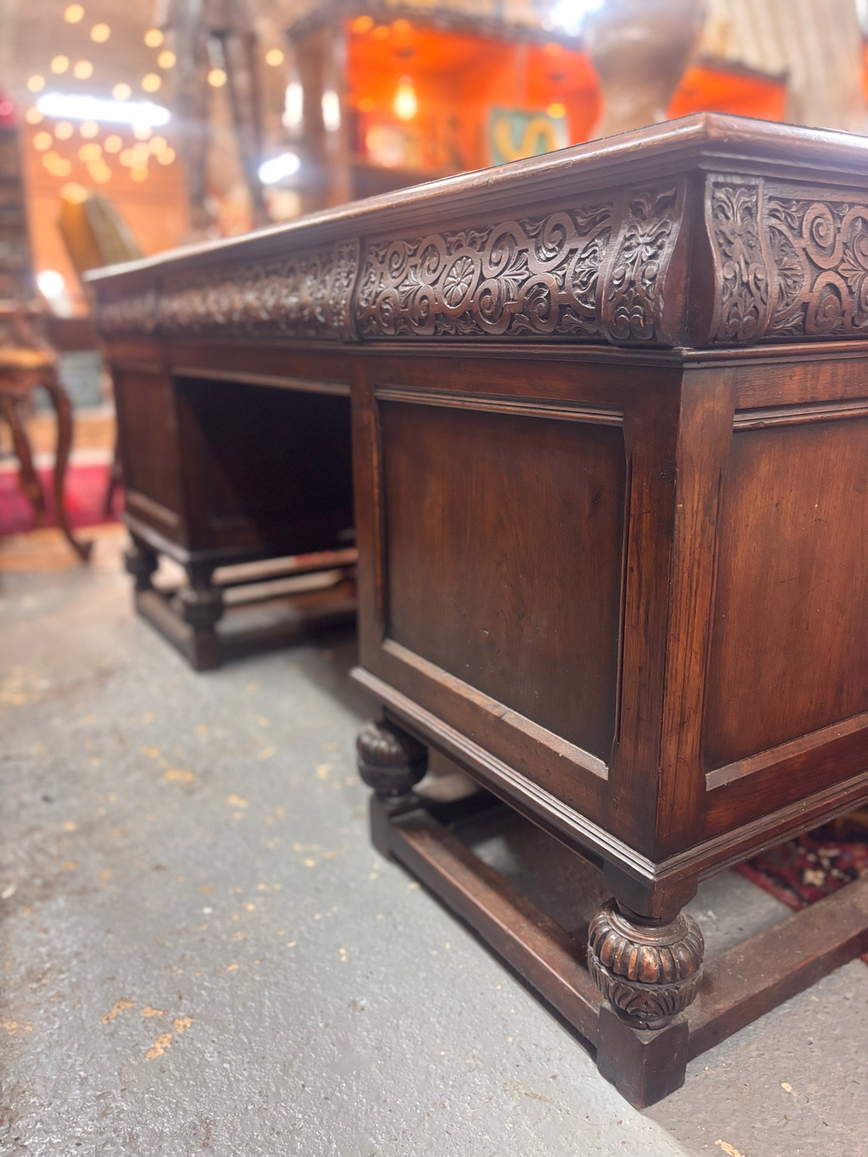 Decorative wooden desk with intricate carvings on a textured floor.