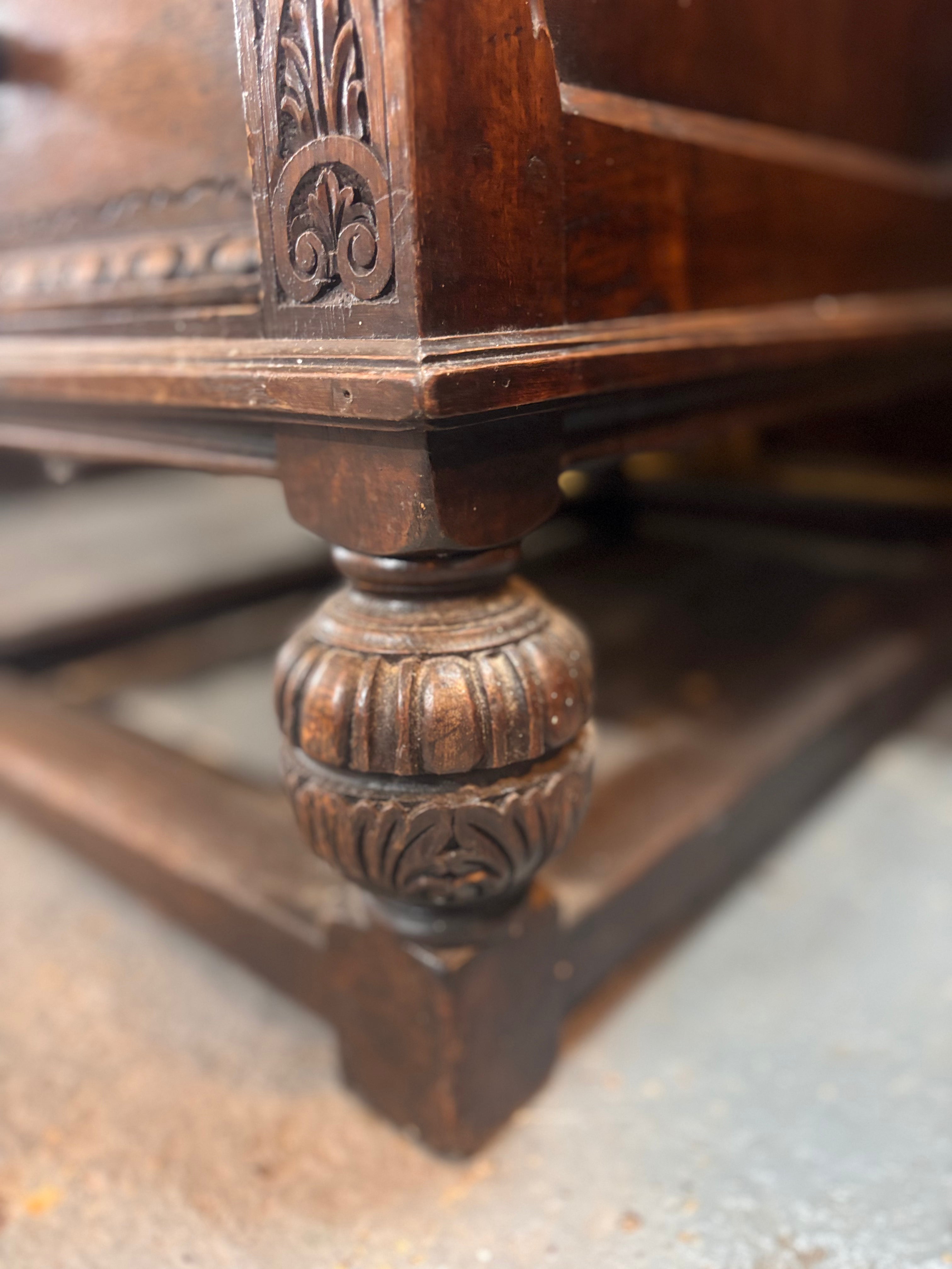 Close-up of a wooden desk leg with intricate carvings on a textured surface.