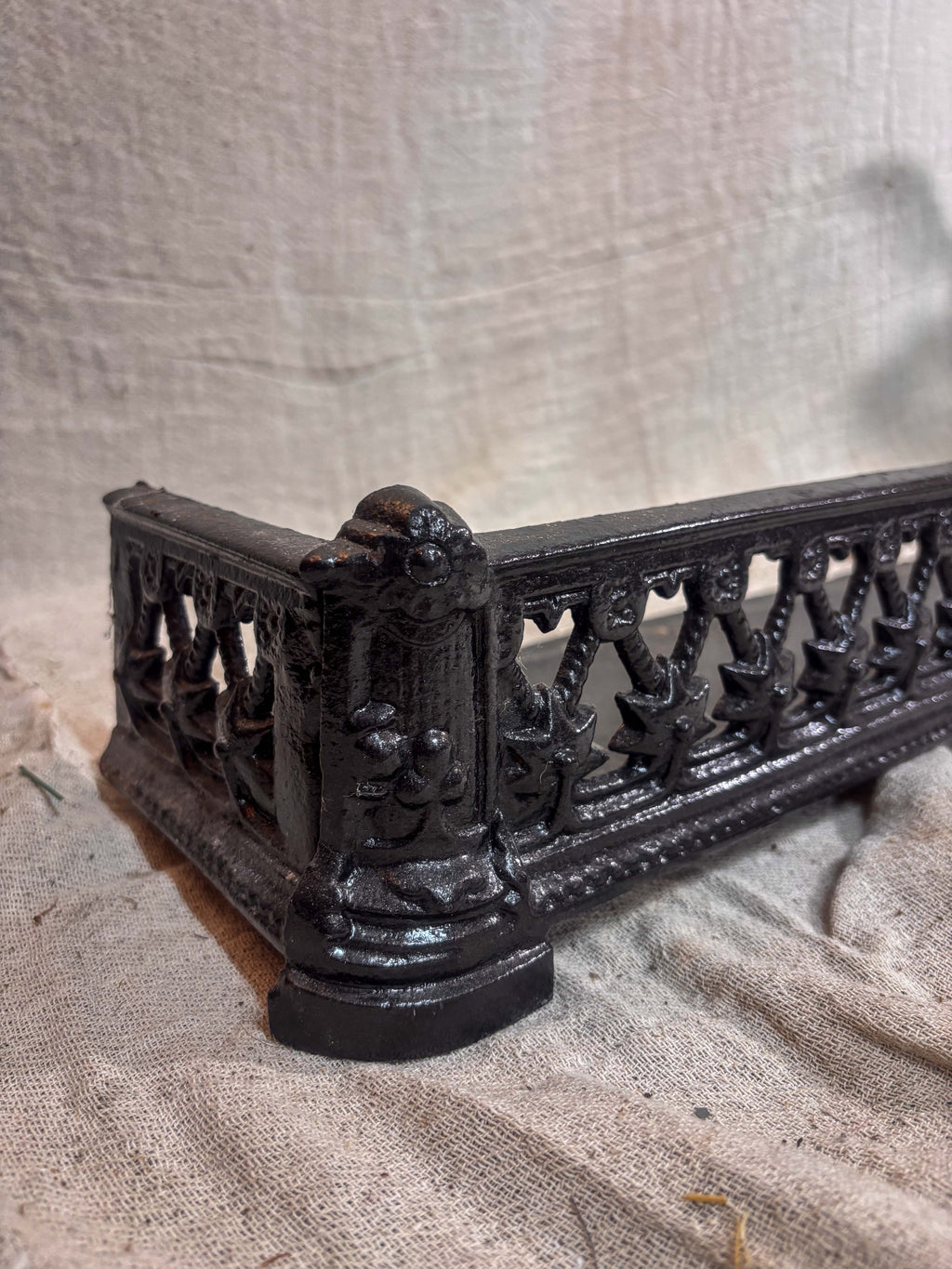 Decorative black metal fireplace fender on a textured beige background