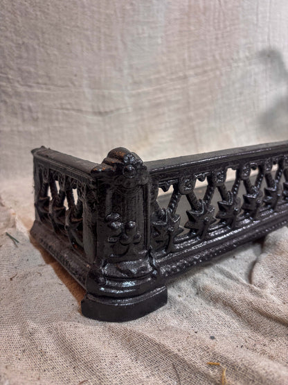 Decorative black metal fireplace fender on a textured beige background