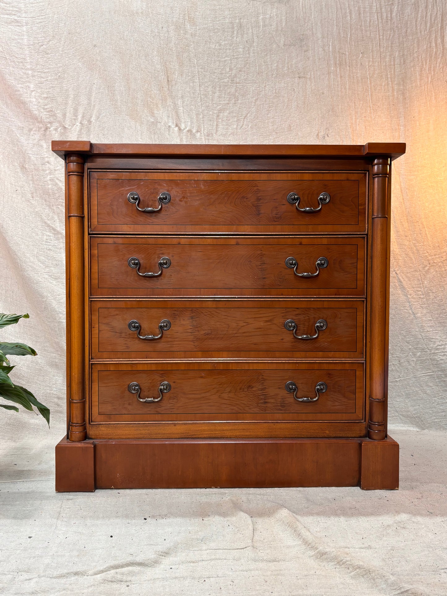 Wooden dresser with four drawers on a textured white background