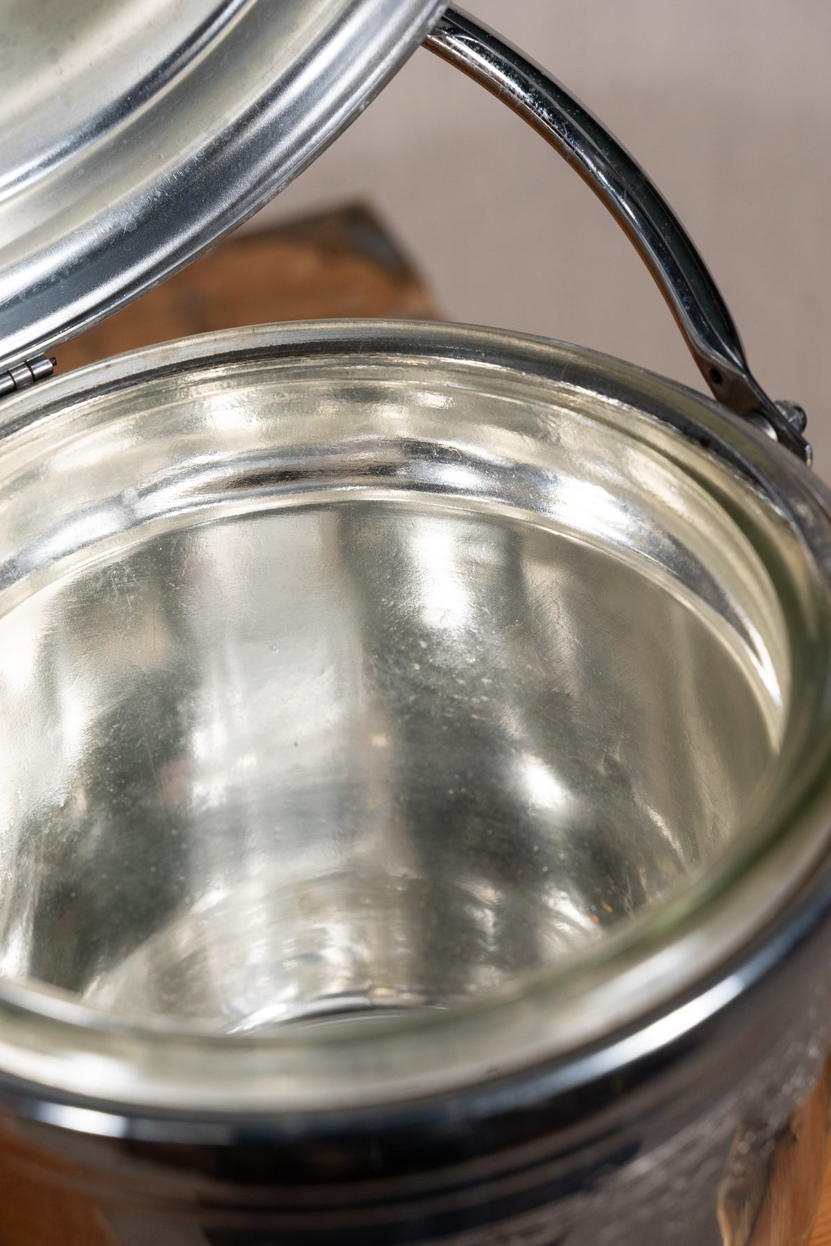 Close-up of a clear glass canister jar with a shiny silver metal lid and handle, showing the transparent glass body and reflective interior.