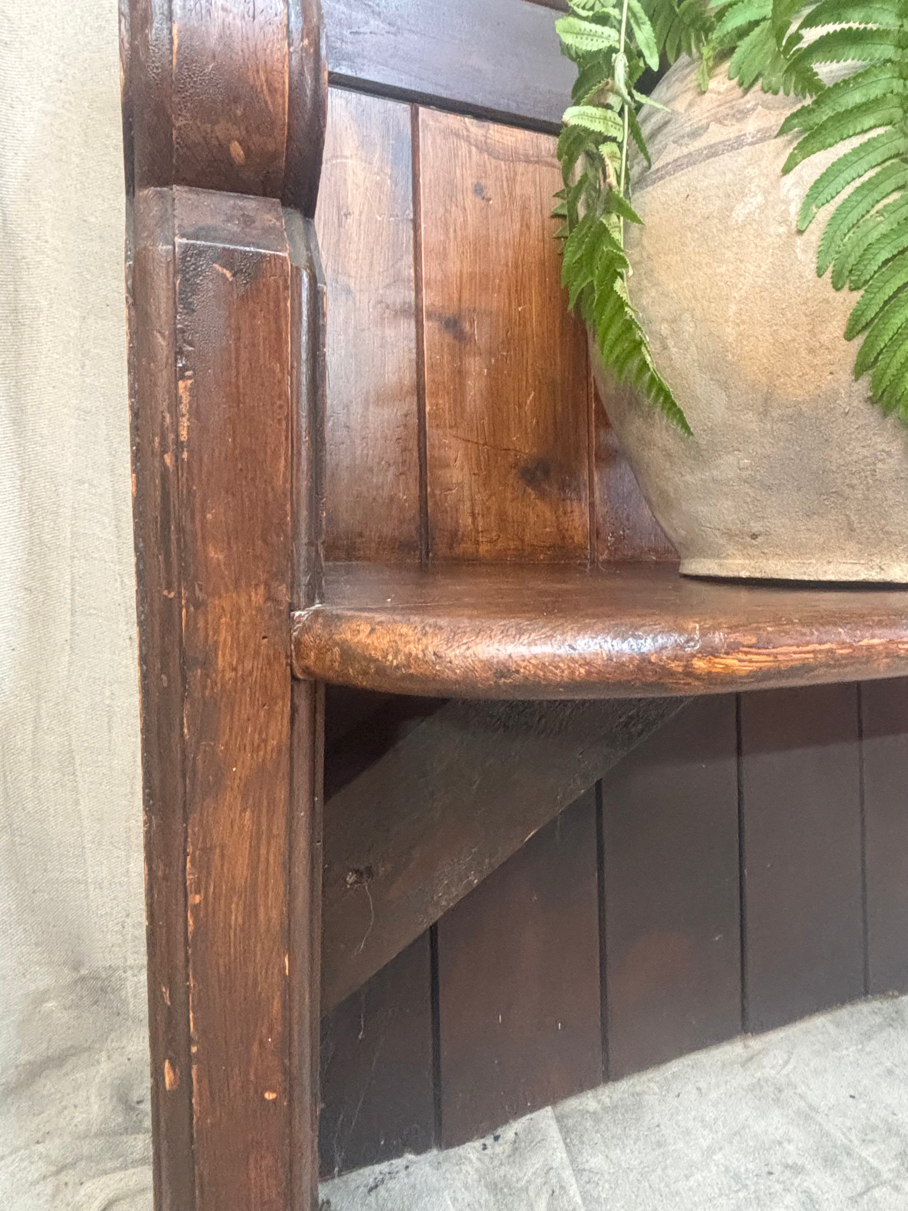 Wooden bench with a textured surface and a plant in the background