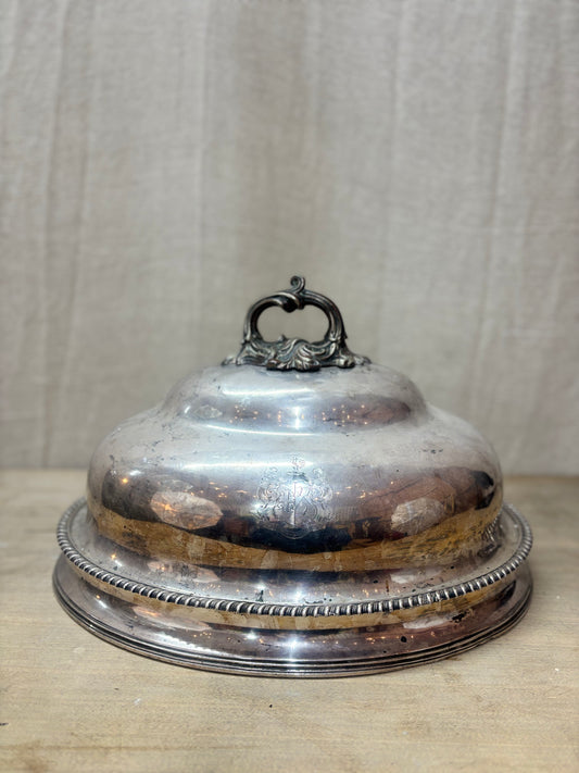 Silver domed cover with decorative handle on a wooden surface