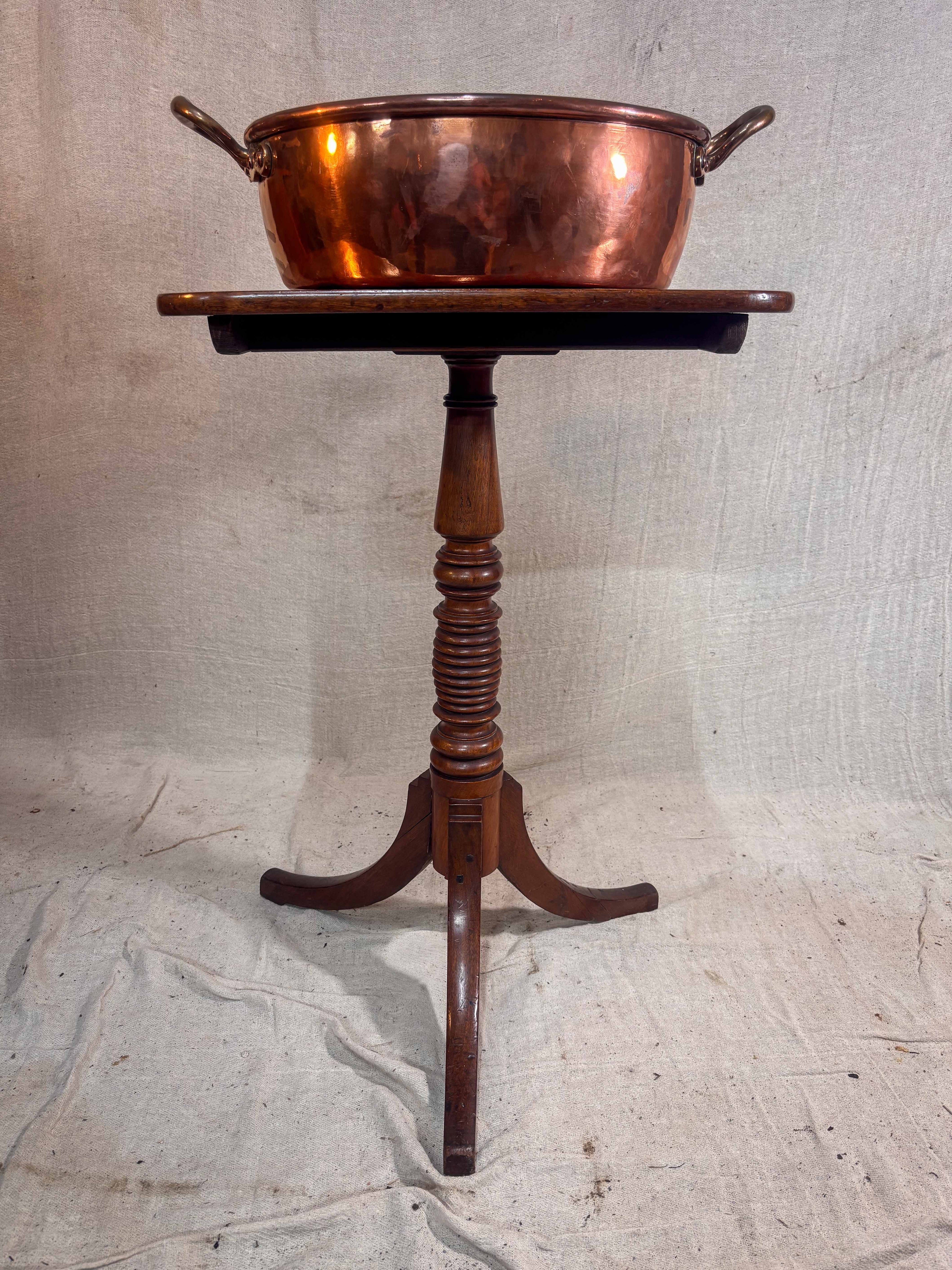 Copper Pan on a wooden stand against a textured wall.