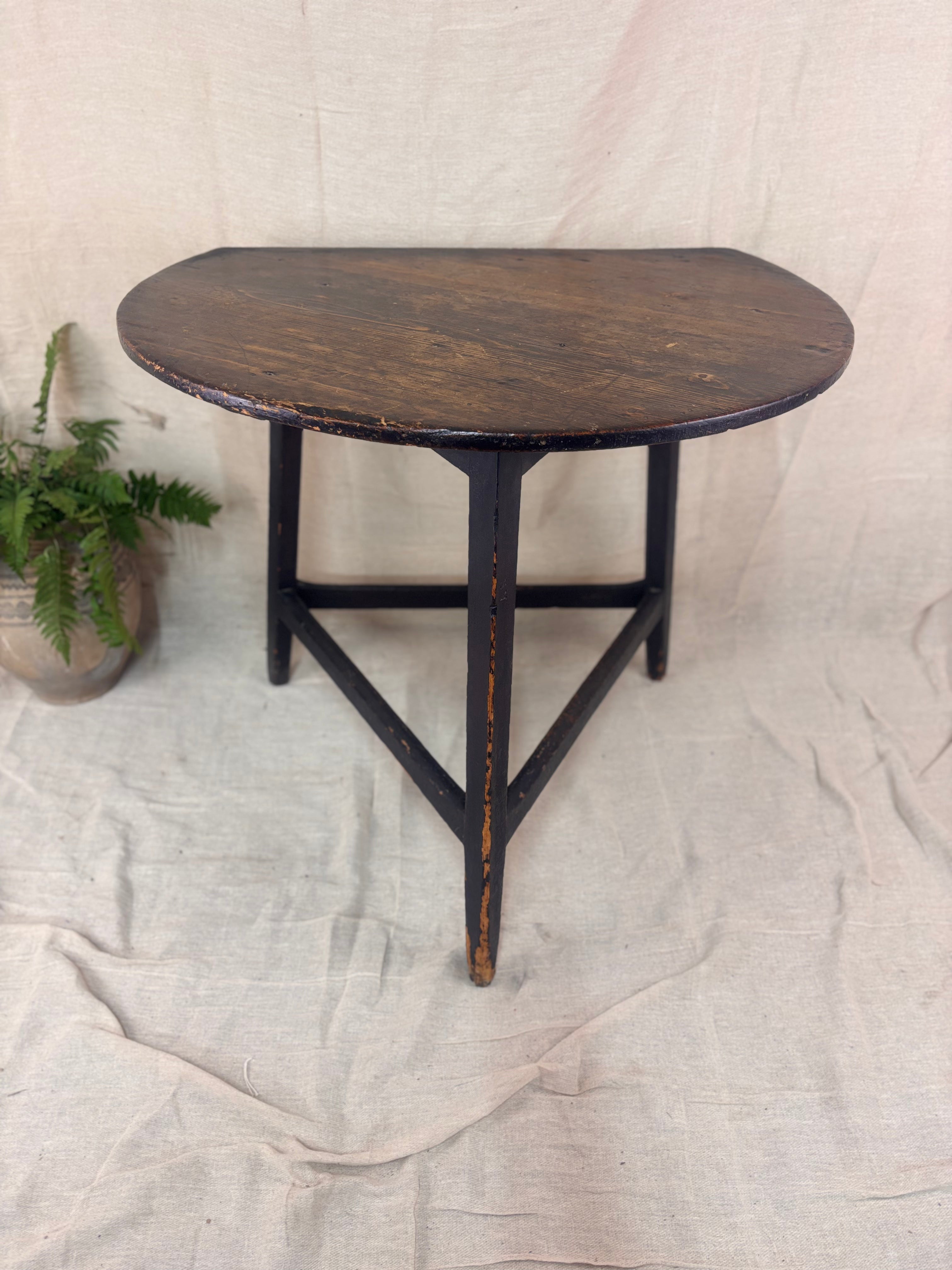 Small round wooden table with a rustic finish on a plain background