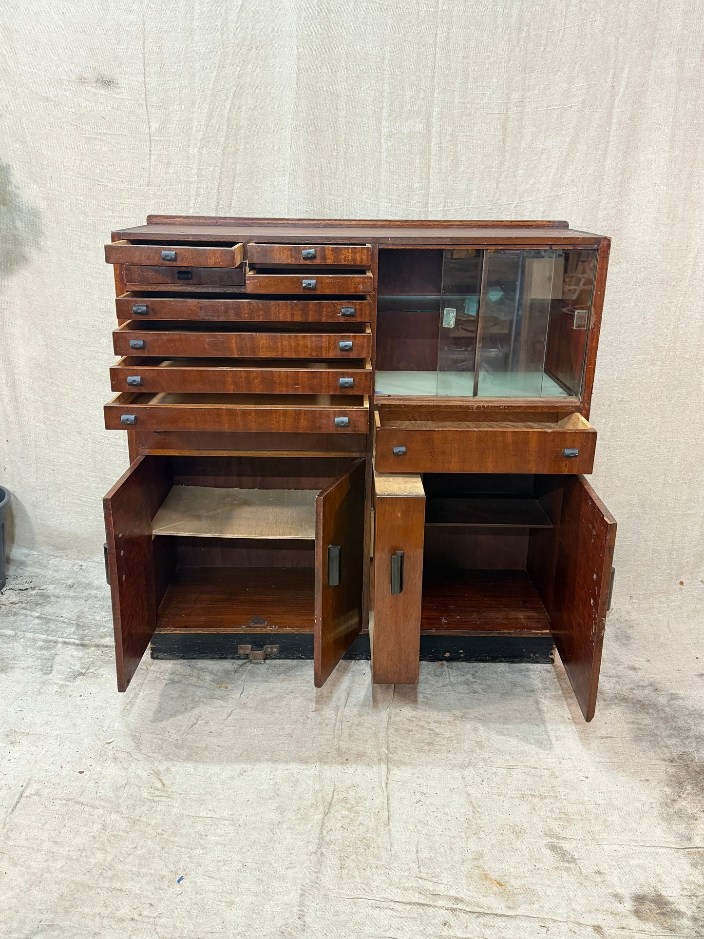 Wooden dentist cabinet with glass doors against a textured white wall.