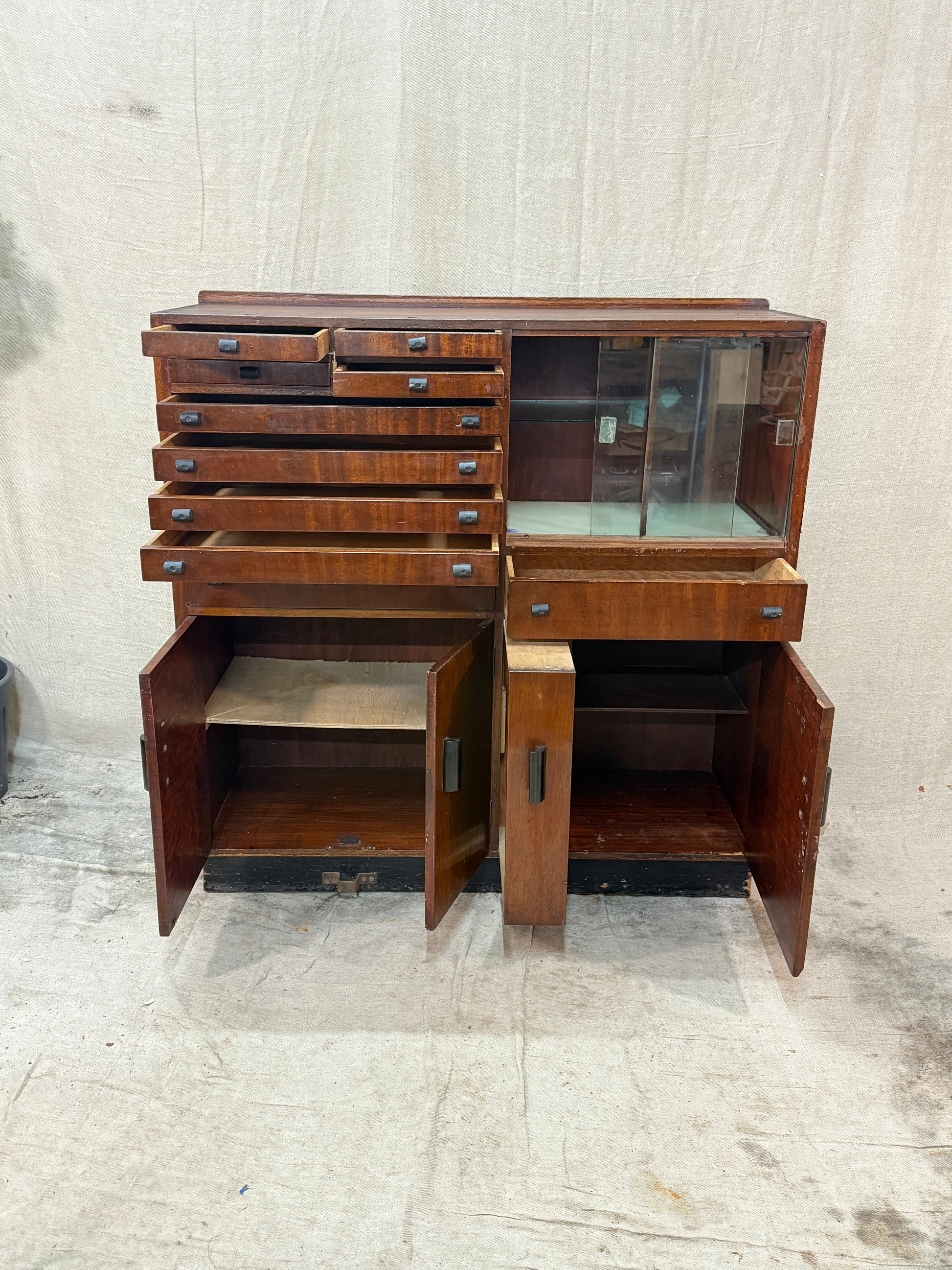 Wooden dentist cabinet with glass doors against a textured white wall.