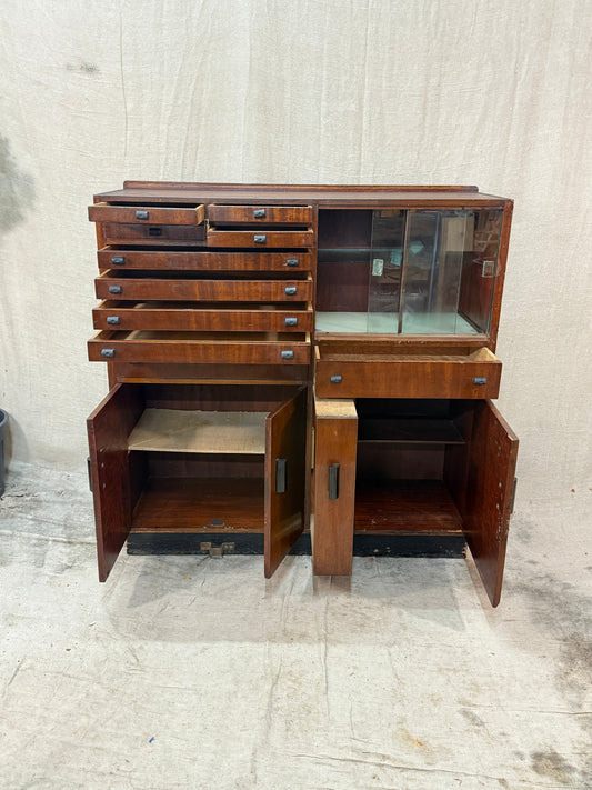 Wooden dentist cabinet with glass doors against a textured white wall.