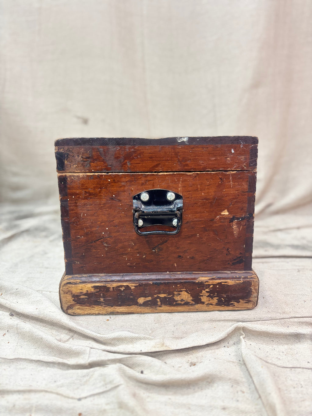 Vintage wooden box with a metal clasp on a beige fabric background