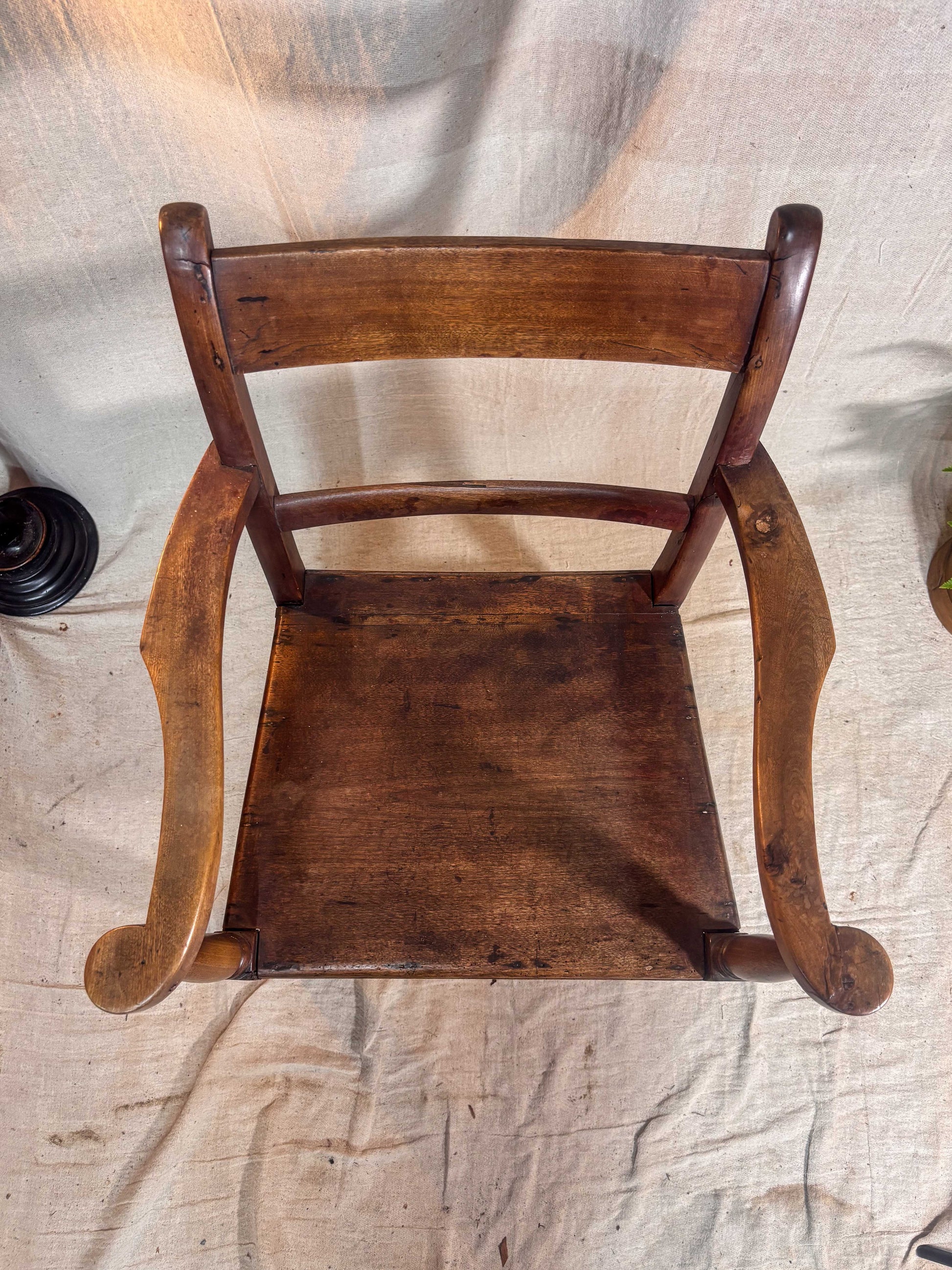 Wooden chair with curved armrests on a textured fabric background