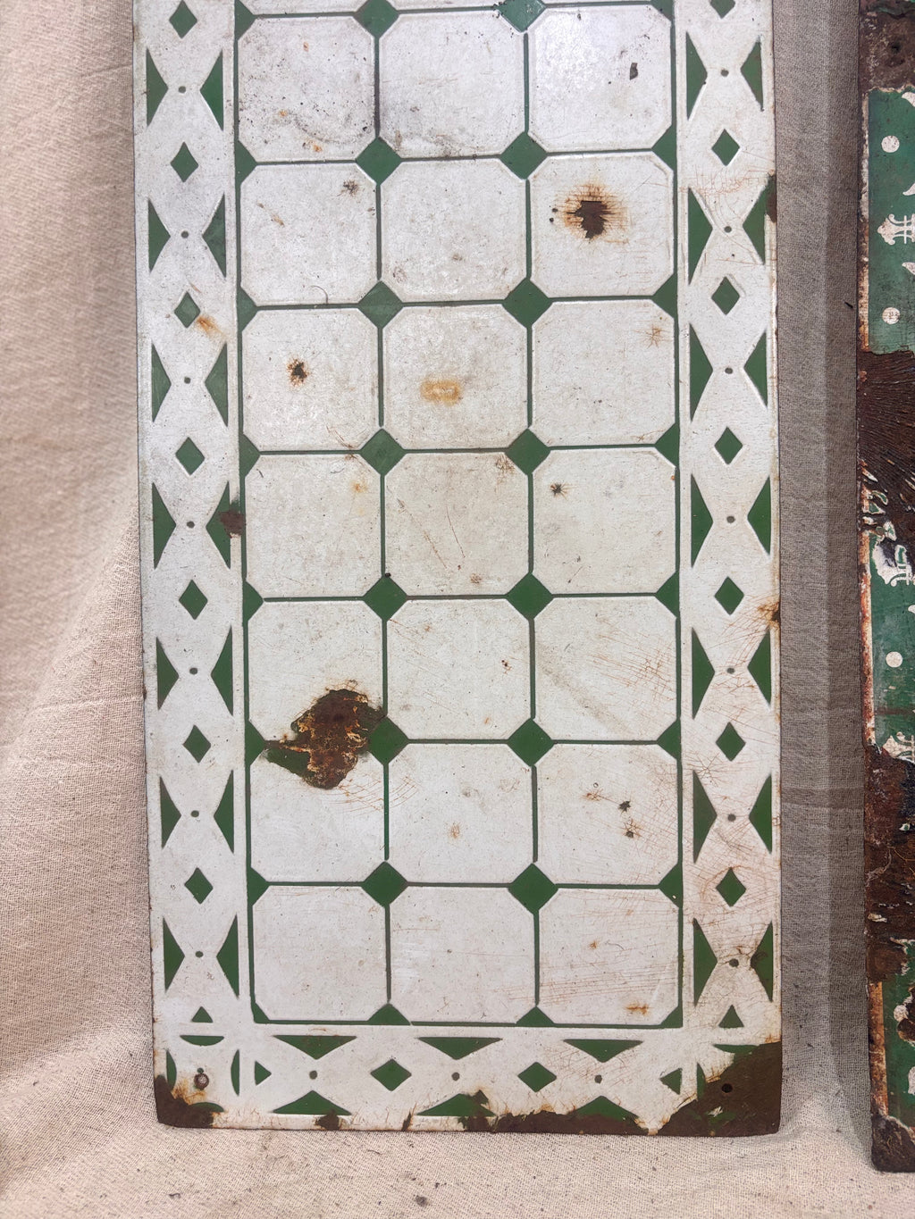 Vintage tile with green and white diamond pattern on a beige background