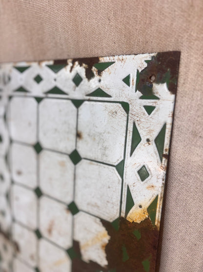 Decorative metal tile with geometric pattern on a beige fabric background