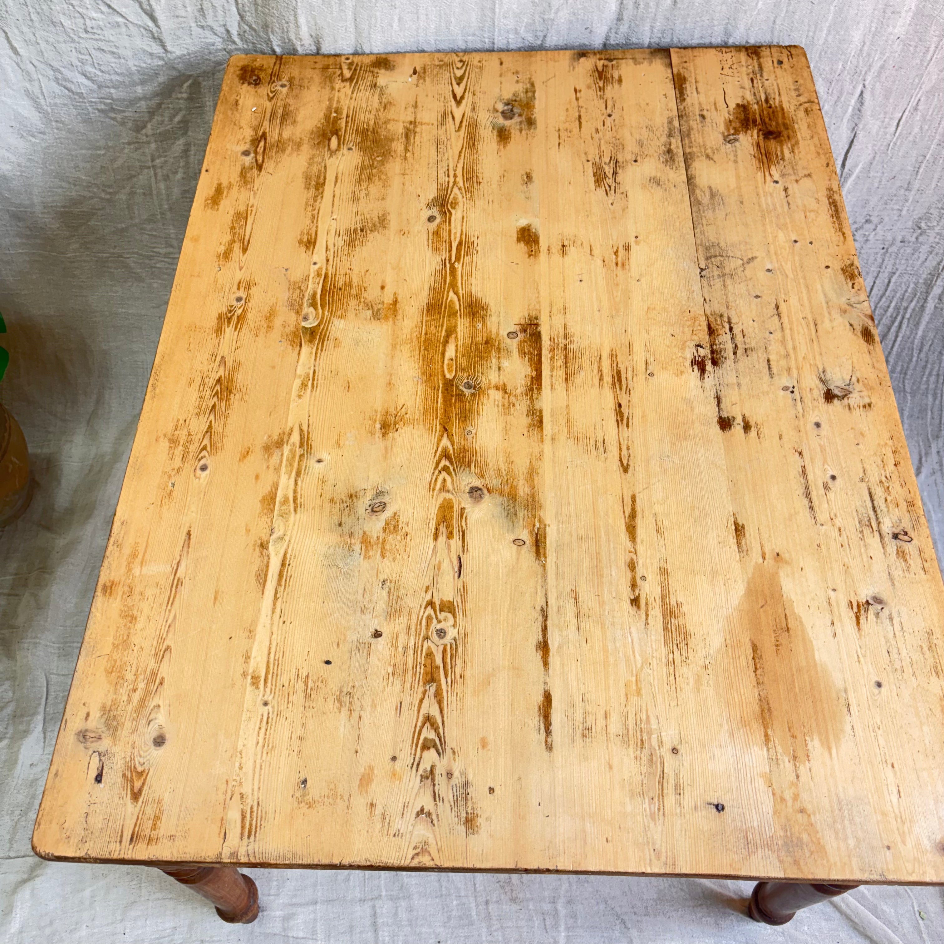 Wooden table top with visible wear and tear on a light-colored fabric background