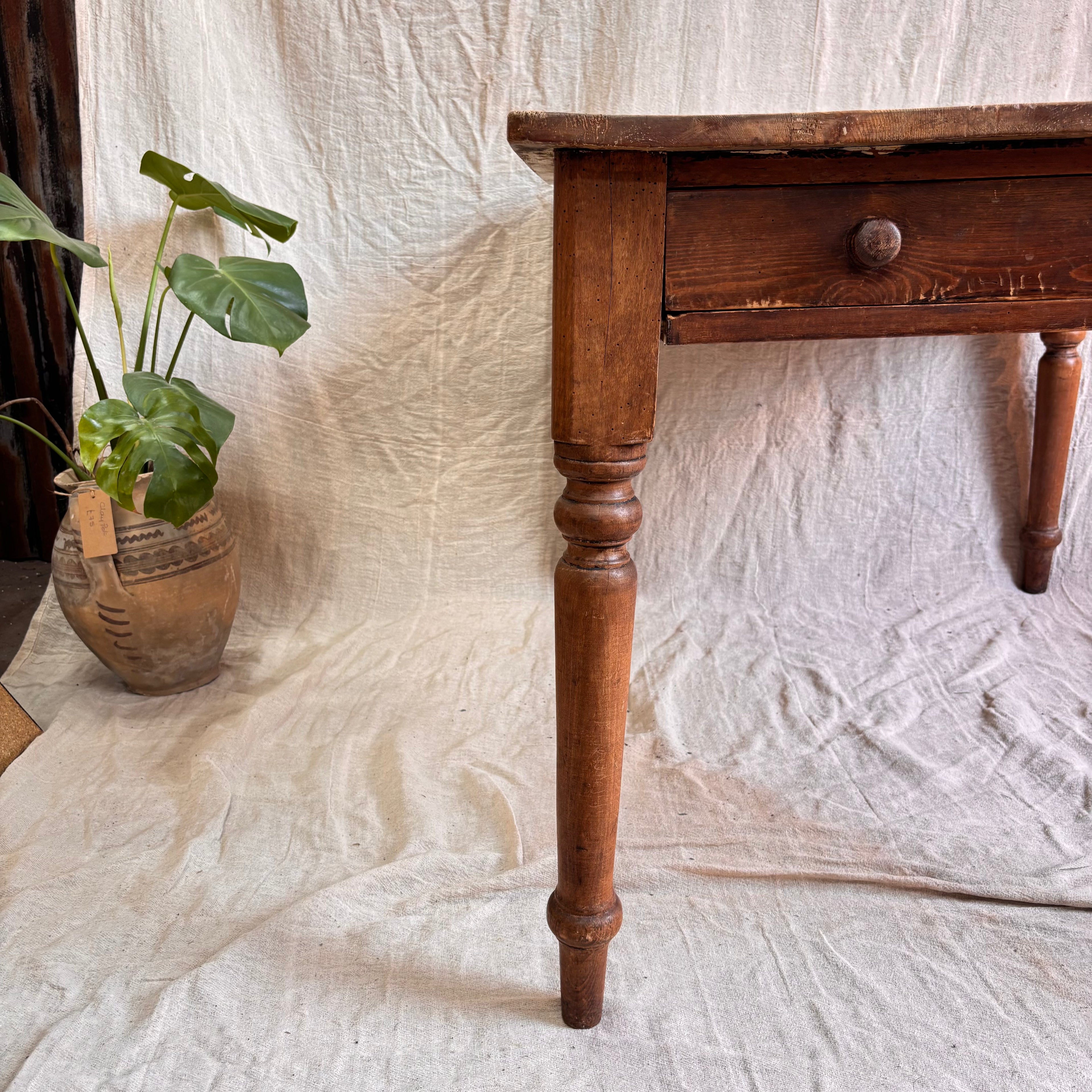 Wooden table with a plant on a textured white fabric background