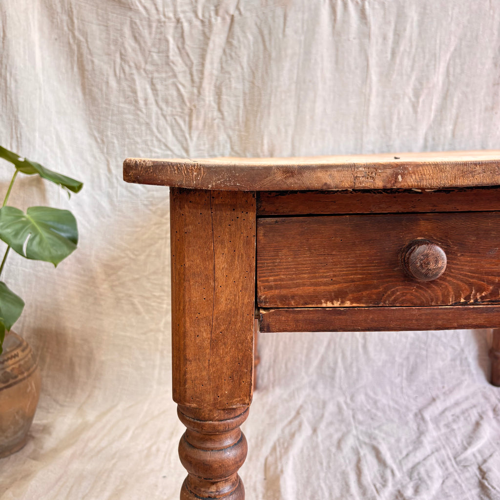 Wooden table with a drawer against a textured white wall