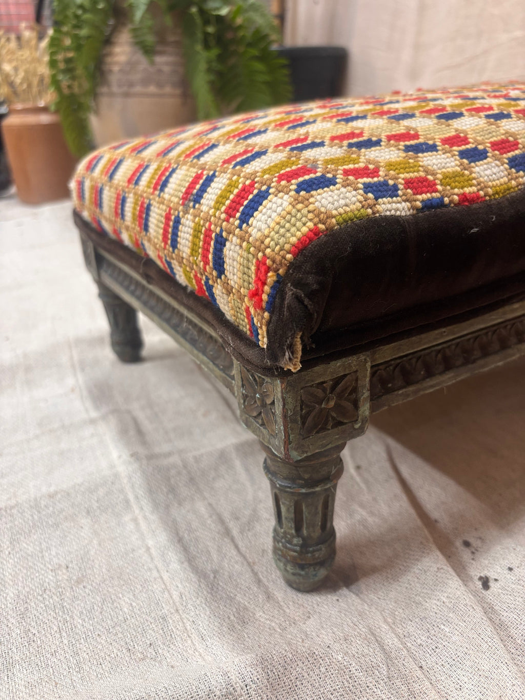 Decorative bench with a multicolored patterned cushion on a textured floor.