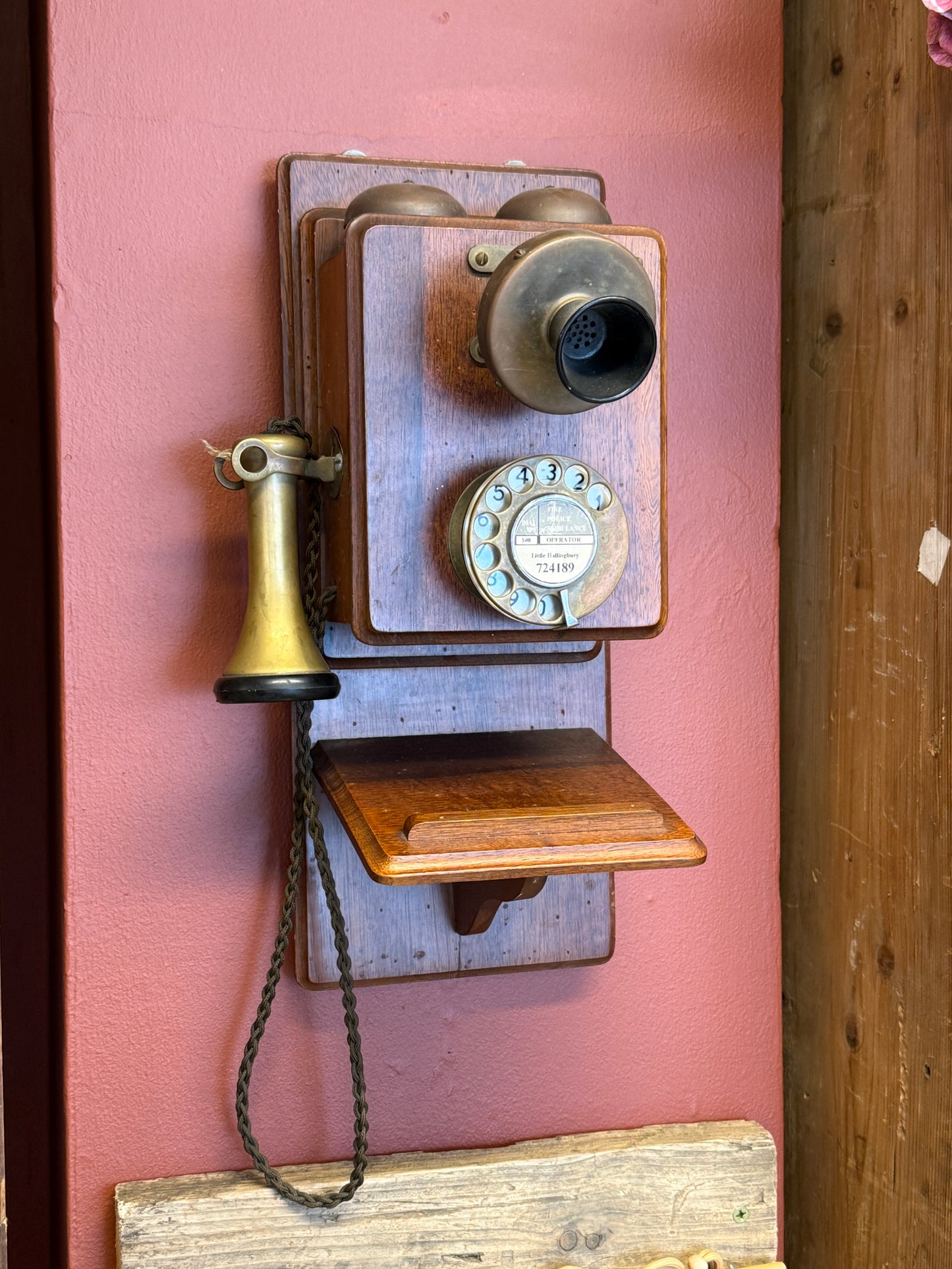 Vintage wooden telephone on a pink surface with a wooden background