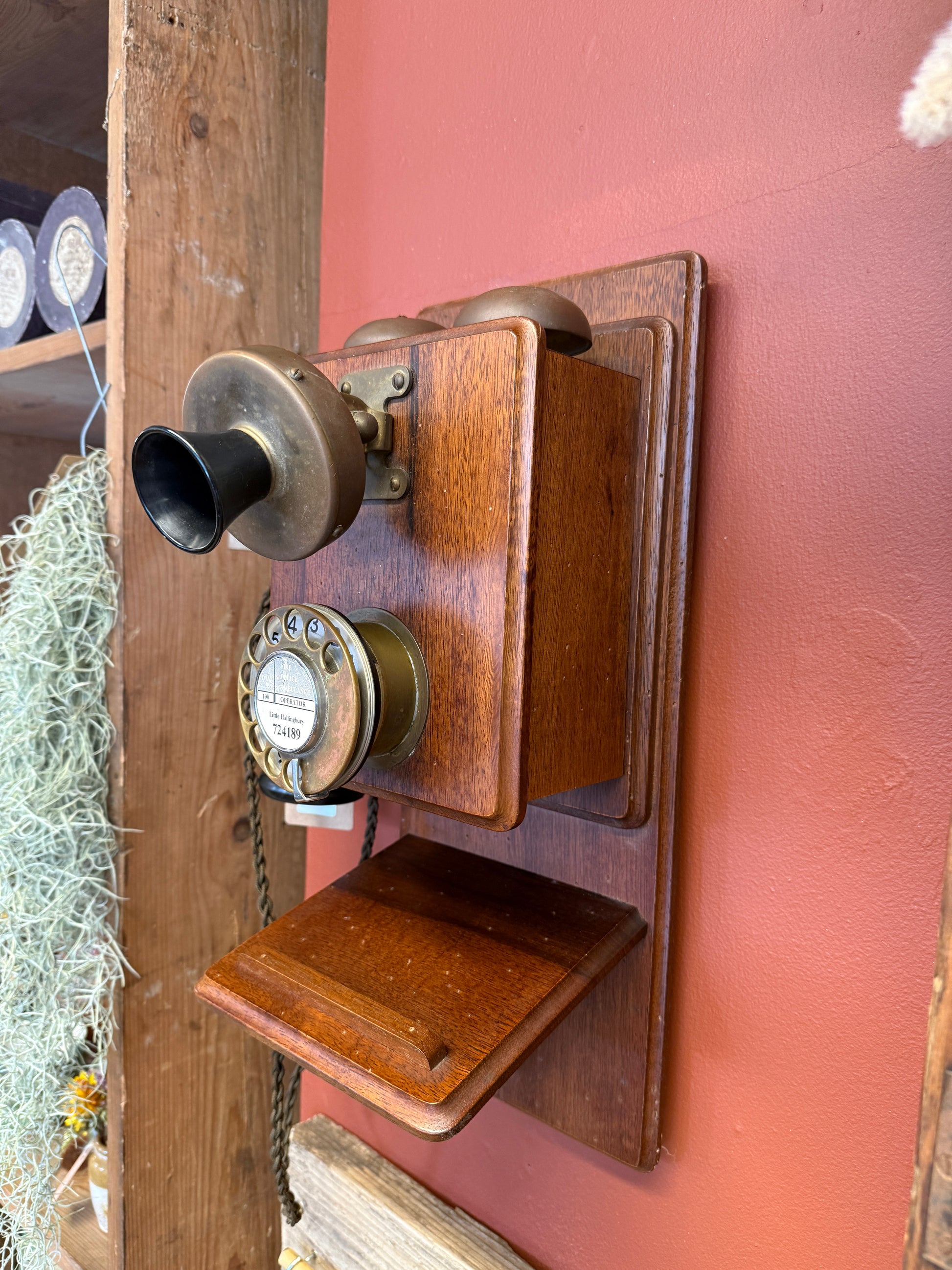 Vintage wooden telephone receiver on a wooden stand with a pink wall background