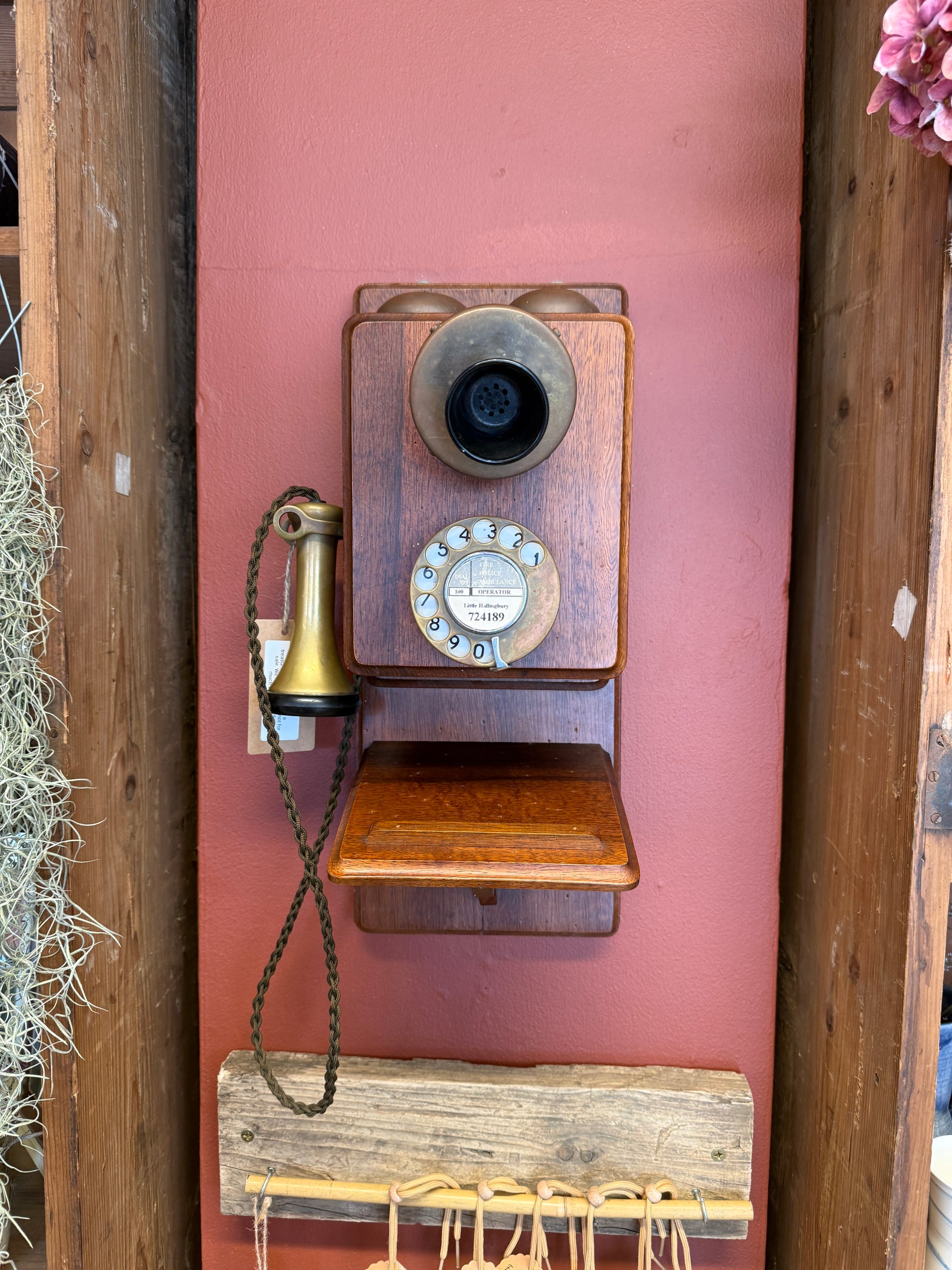 Vintage wooden telephone on a pink surface with a wooden base.