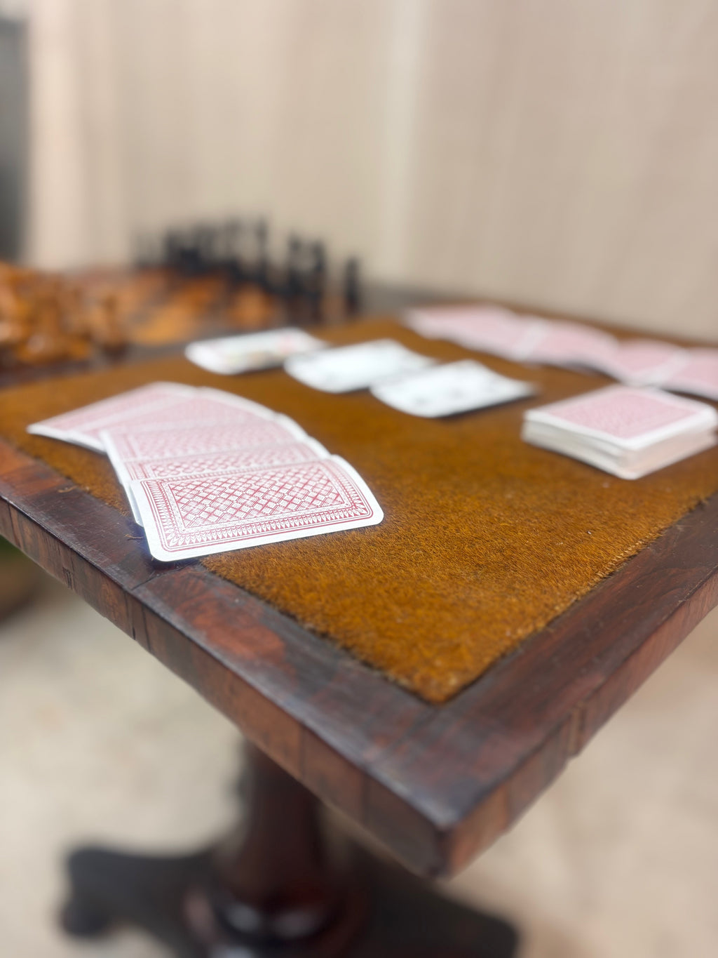 Wooden table with playing cards and chess pieces on a neutral background