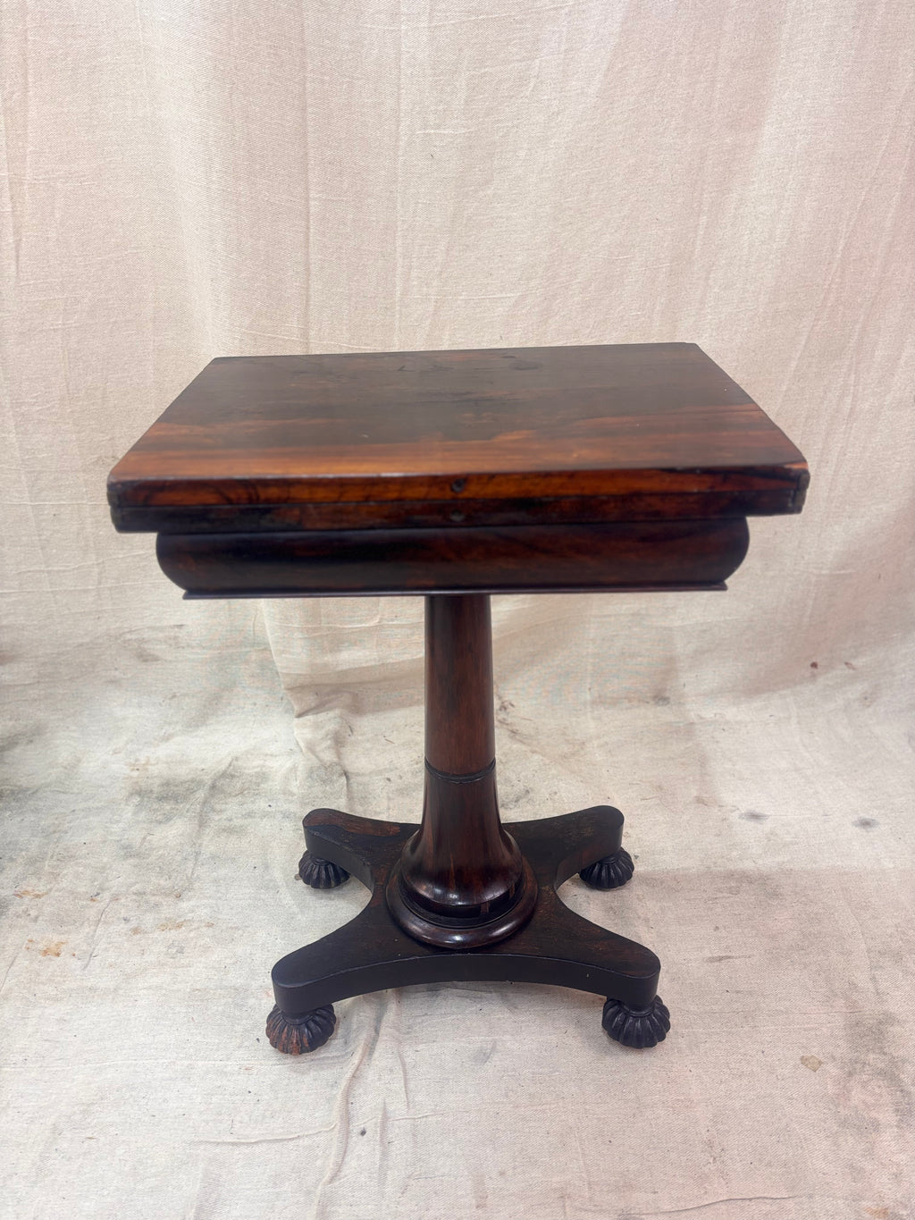 Antique rosewood fold-over games table shown closed on a cream background. 