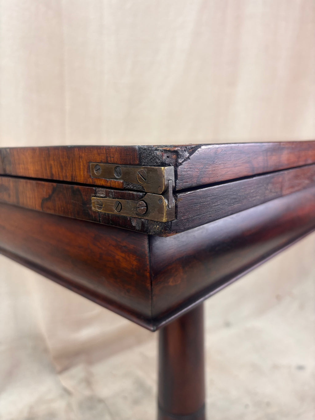Close-up of a wooden table corner with metal brackets on a neutral background