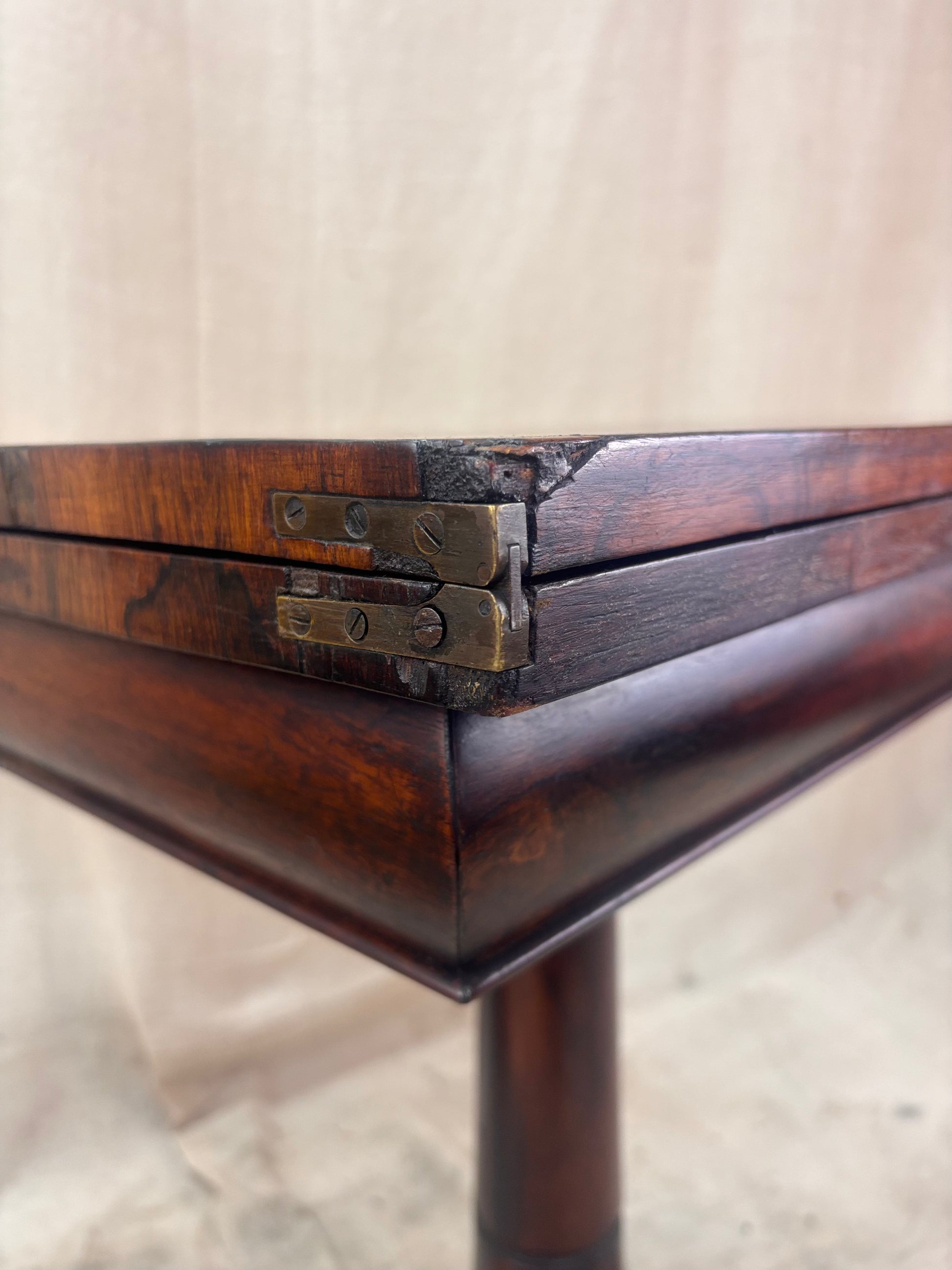 Close-up of a wooden table corner with metal brackets on a neutral background