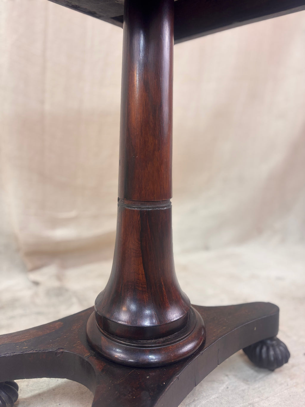 Wooden pedestal base of a table with a plain background