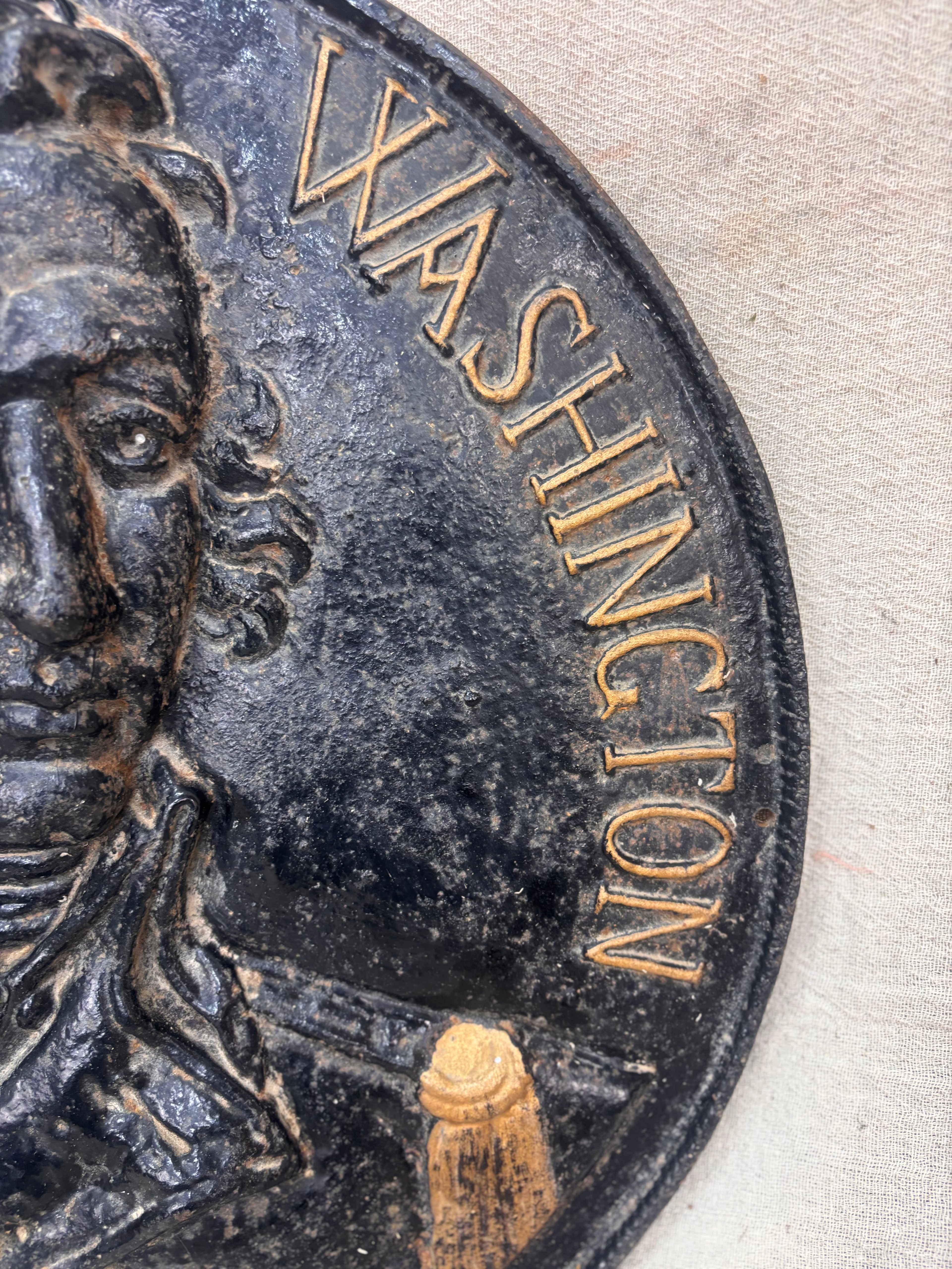 Close-up of a cast iron plaque with 'Washington' inscribed on a textured surface