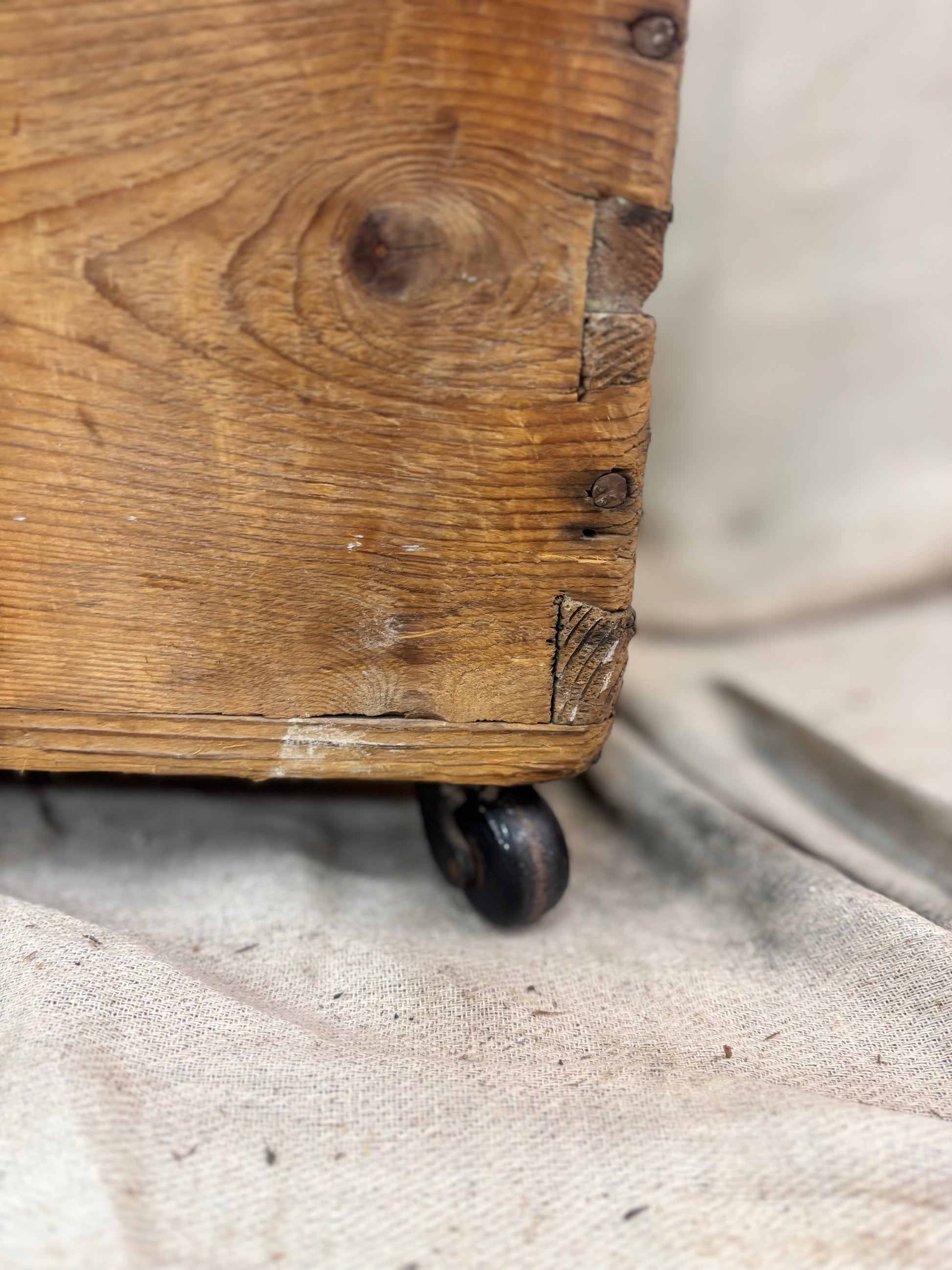 Close-up of a wooden box with a wheel on a textured surface