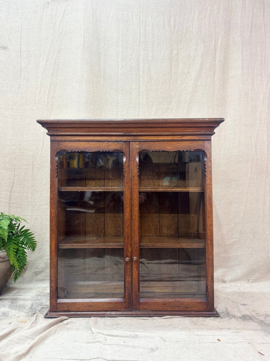 A Glazed oak bookcase on a light backdrop