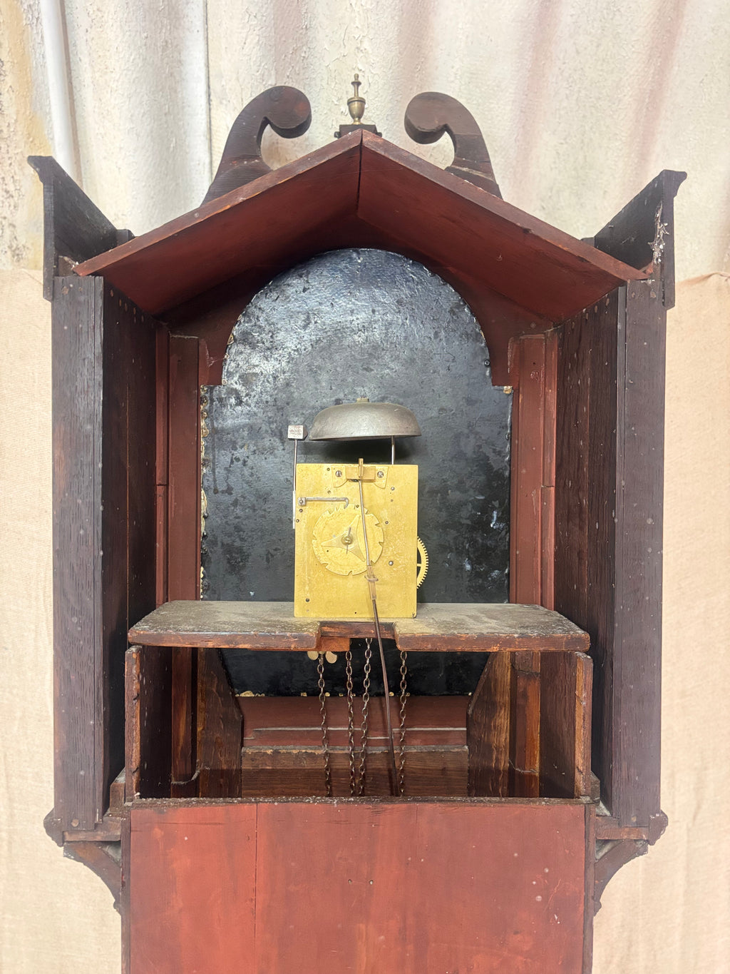 A the back of antique Longbody Clock against a cloth Backdrop