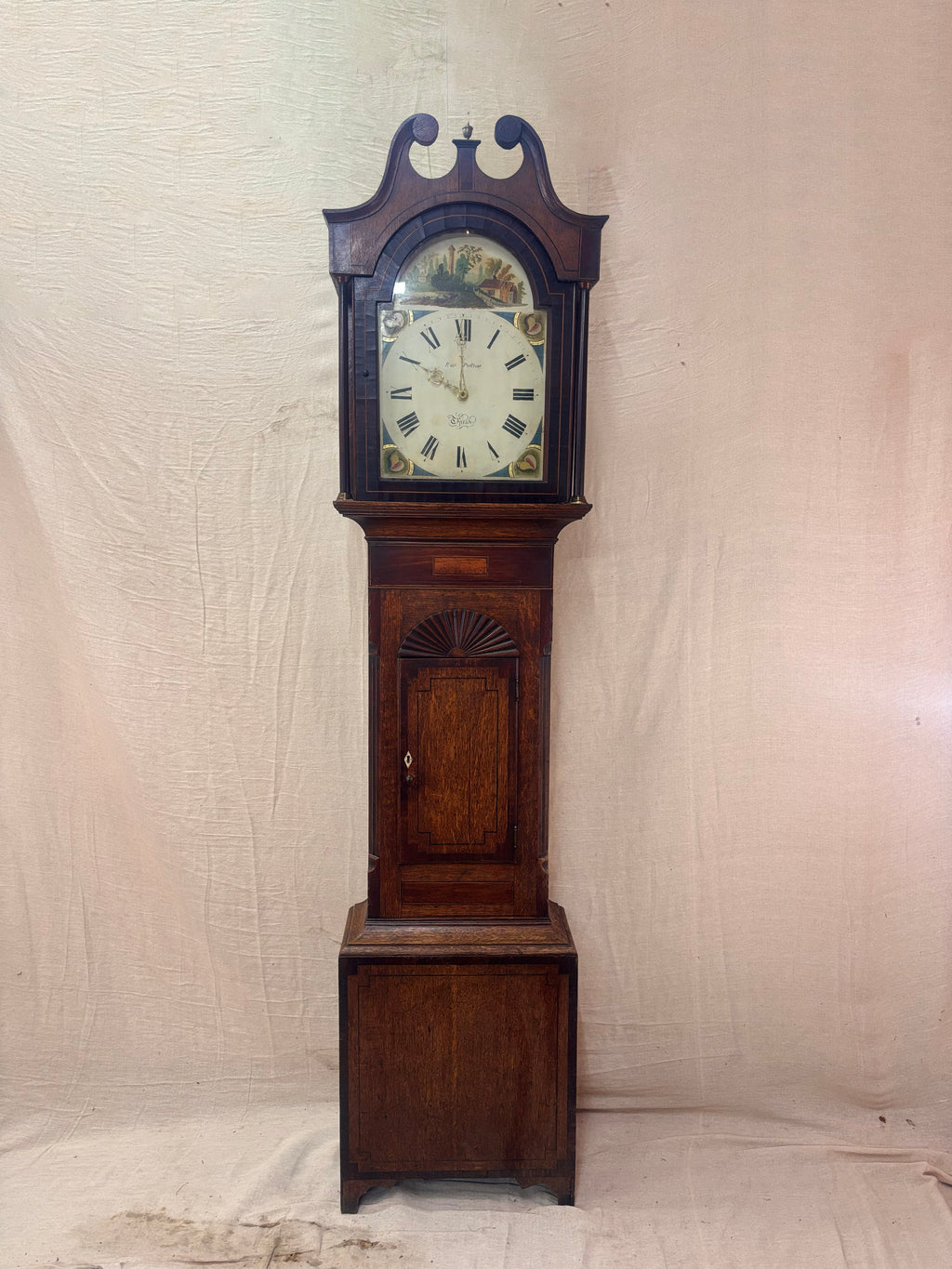 A antique Longbody Clock against a cloth Backdrop
